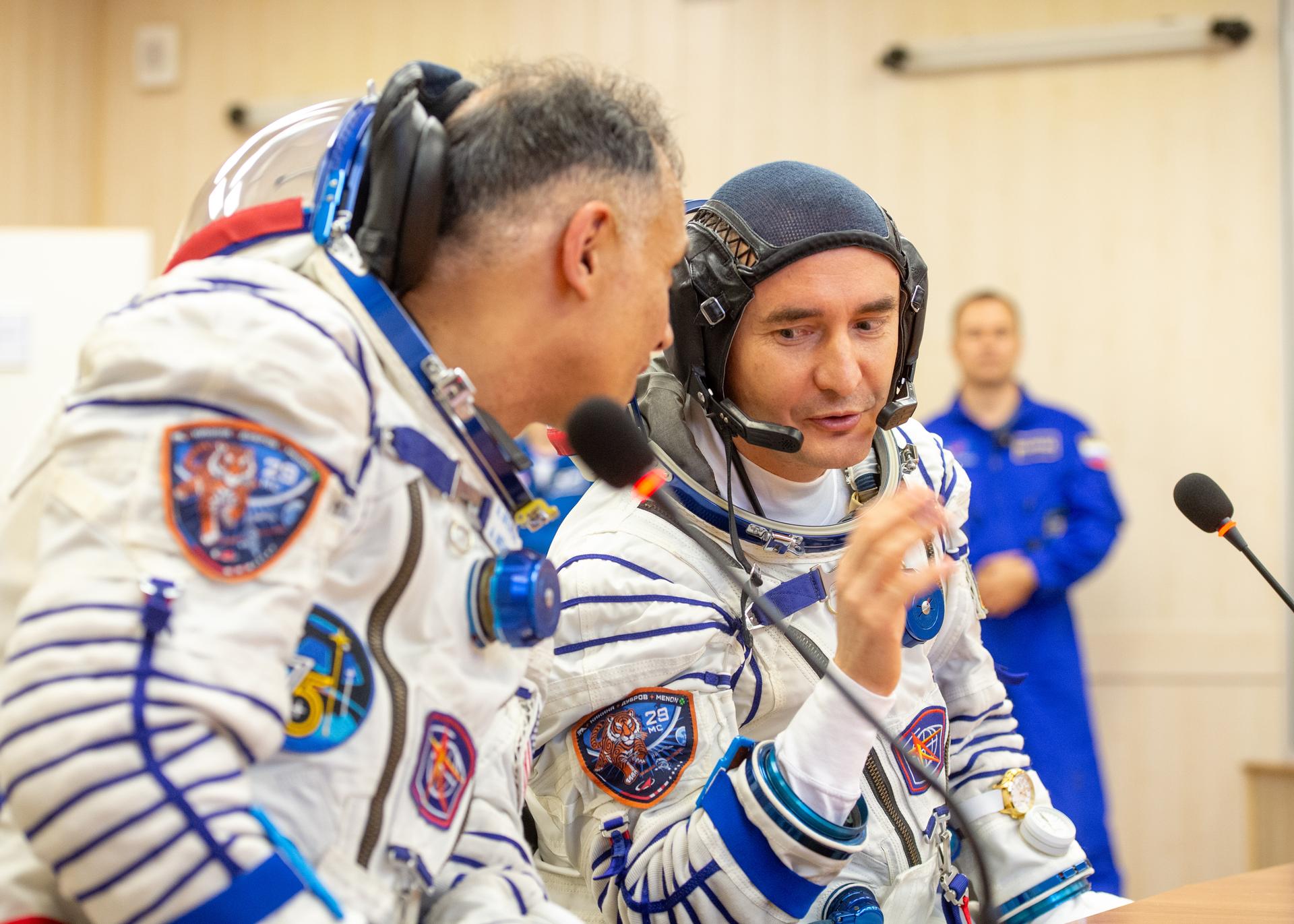 Expedition 75 NASA astronaut Anil Menon, left, and Roscosmos cosmonaut Pyotr Dubrov, talk to family and friends after they and Roscosmos cosmonaut Anna Kikina had their Russian Sokol suits pressure checked for their Soyuz launch to the International Space Station Tuesday, July 14, 2026 in Baikonur, Kazakhstan. Photo Credit: (NASA/GCTC/Pavel Shvets)