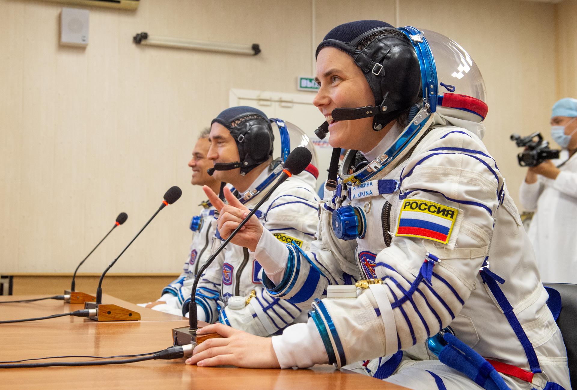 Expedition 75 Roscosmos cosmonaut Anna Kikina, foreground, Roscosmos cosmonaut Pyotr Dubrov, and NASA astronaut Anil Menon, left, talk with friends and family after having their Russian Sokol suits pressure checked as they prepare for their Soyuz launch to the International Space Station Tuesday, July 14, 2026 in Baikonur, Kazakhstan. Photo Credit: (NASA/GCTC/Pavel Shvets)