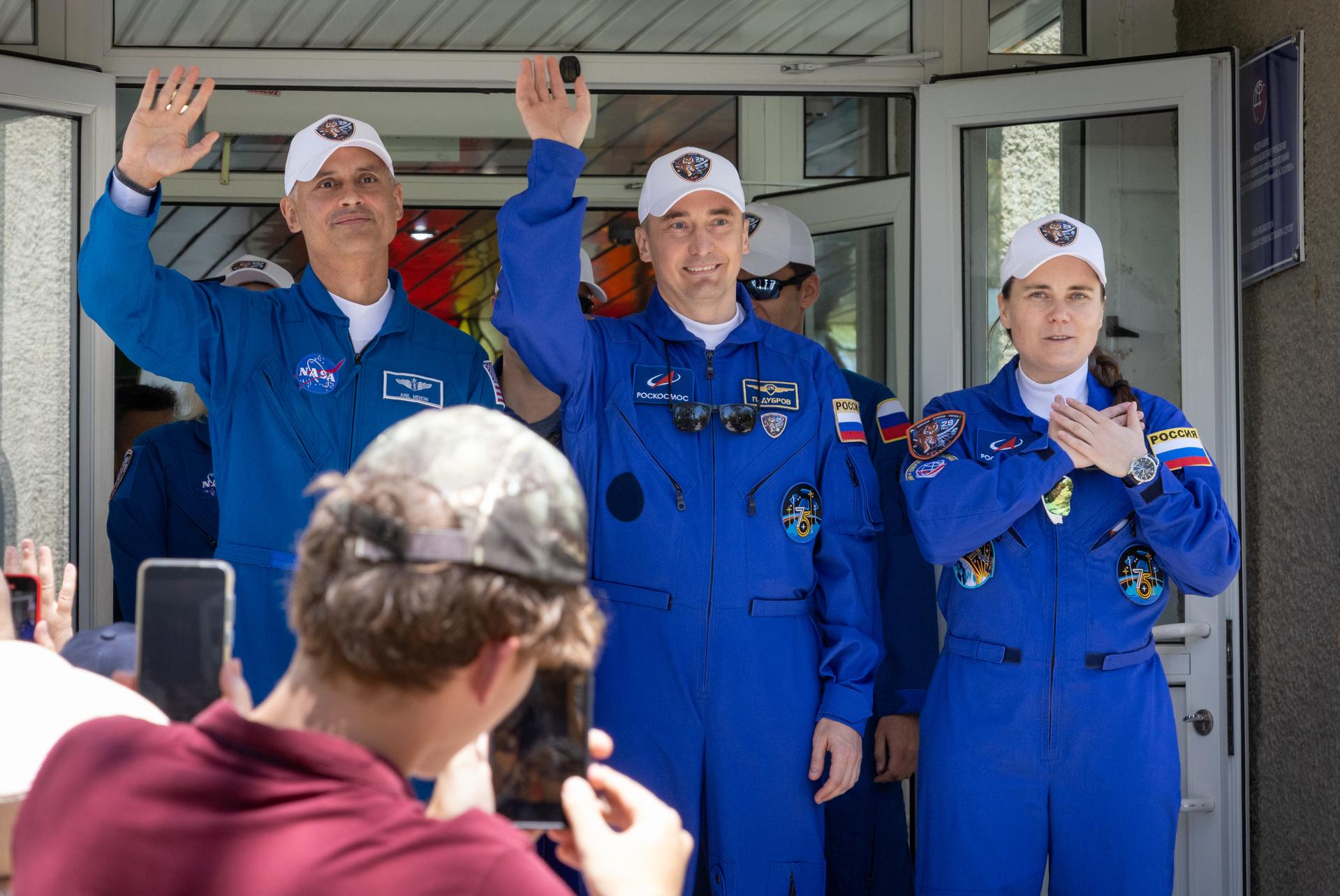Expedition 75 crewmemebers: NASA astronaut Anil Menon, left, Roscosmos cosmonauts Pyotr Dubrov, and Anna Kikina, right, wave as they depart the Cosmonaut Hotel to suit-up for their Soyuz launch, Tuesday, July 14, 2026, in Baikonur, Kazakhstan. The launch will send Menon, Dubrov, and Kikina on a mission to the International Space Station. Photo Credit: (NASA/Victor Zelentsov)