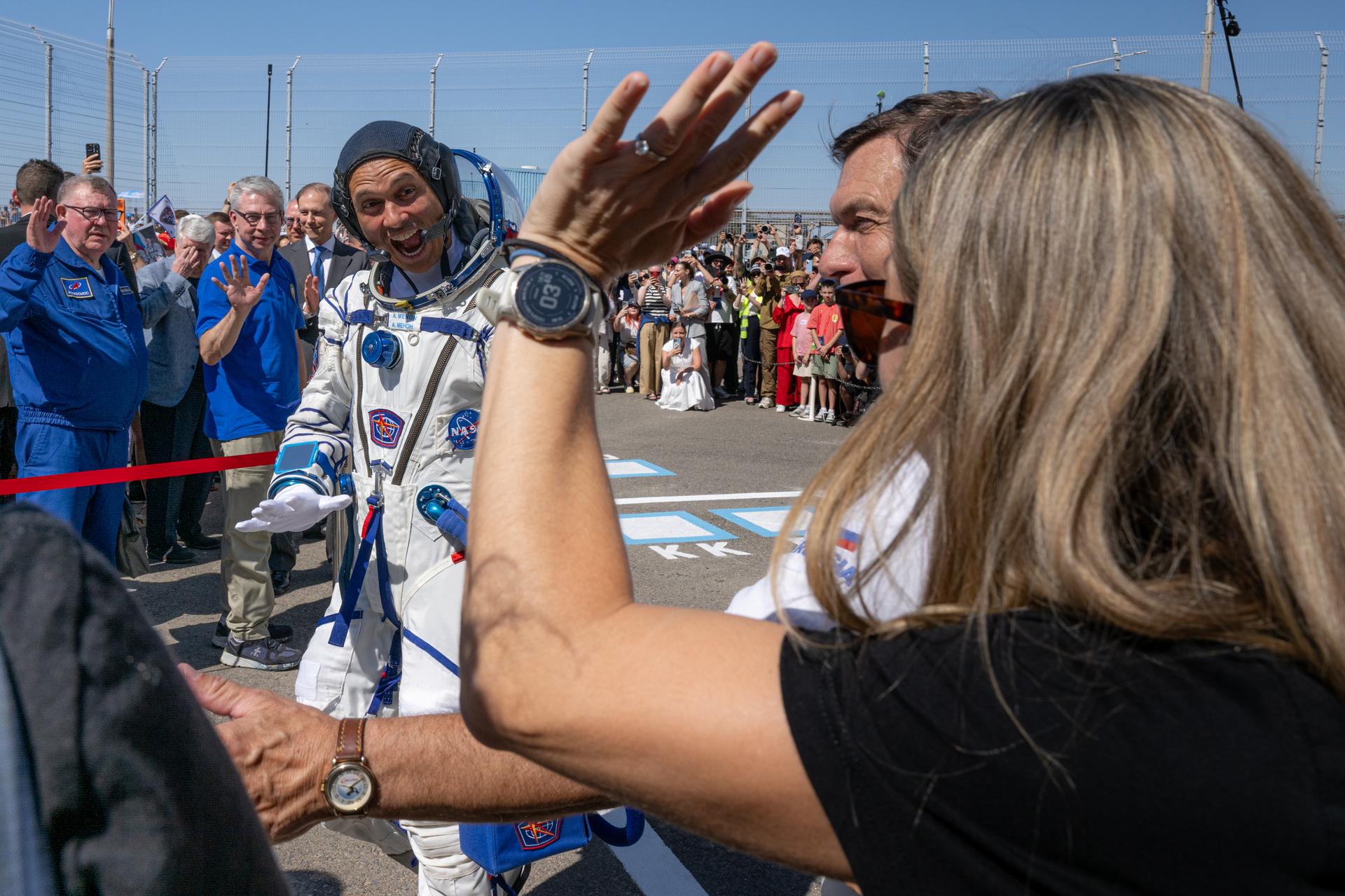 Expedition 75 crewmember NASA astronaut Anil Menon, left, waves to his wife, NASA astronaut candidate Anna Menon, right, while departing building 254 before launch, Tuesday, July 14, 2026, at the Baikonur Cosmodrome in Kazakhstan. The launch will send NASA astronaut Anil Menon and Roscosmos cosmonauts Pyotr Dubrov and Anna Kikina to the International Space Station aboard the Soyuz MS-29 spacecraft. Photo Credit: (NASA/John Kraus)