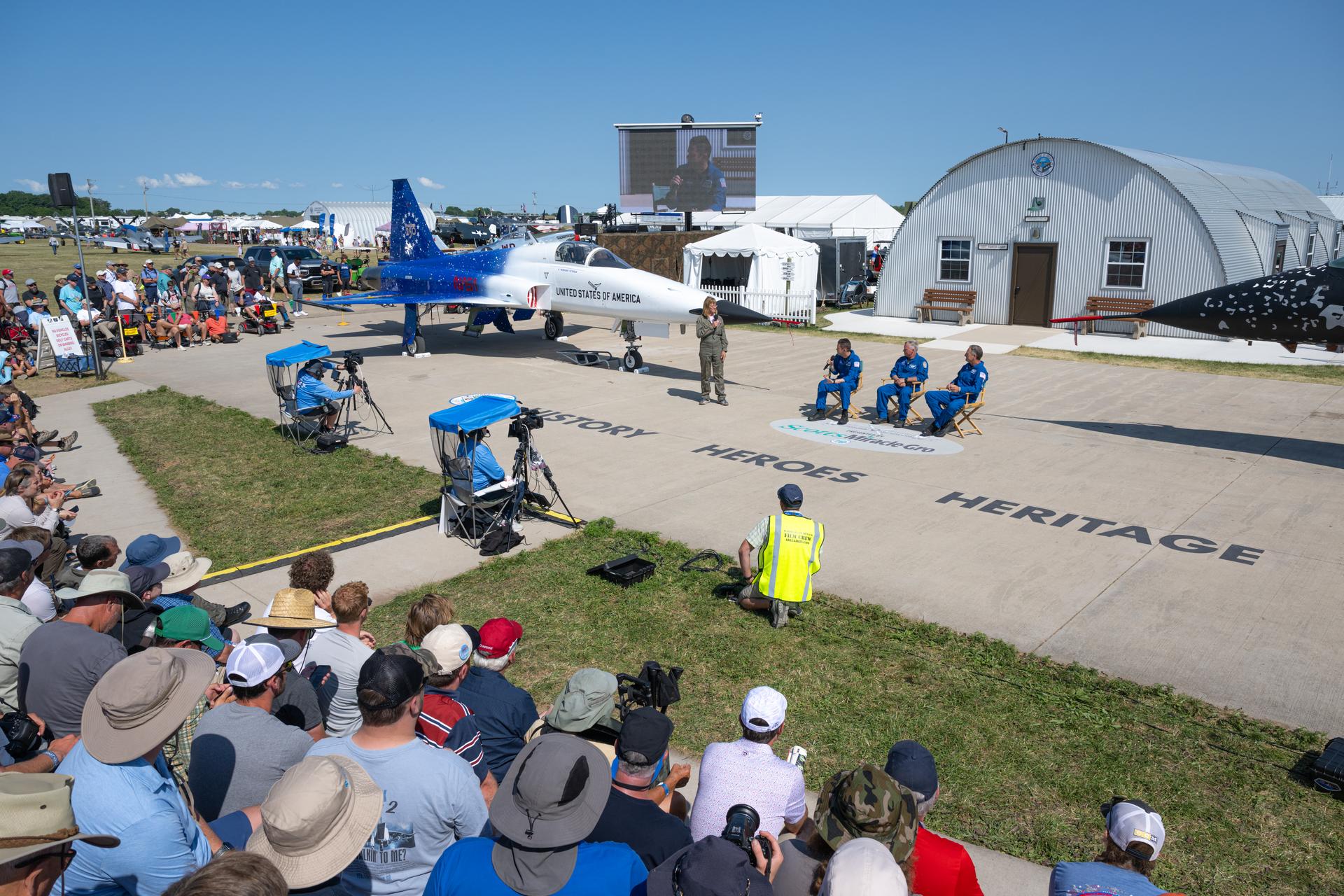 NASA Administrator Jared Isaacman, left, speaks during a “Warbirds in Review” presentation, Thursday, July 23, 2026, at EAA AirVenture Oshkosh at Wittman Regional Airport in Oshkosh, Wis. Isaacman was joined by Todd Ericson, senior advisor the administrator, center, and Sean Gustafson, senior advisor to the administrator, right, to discuss NASA’s efforts in air and space, their aviation experience, and more. Photo Credit: (NASA/John Kraus)
