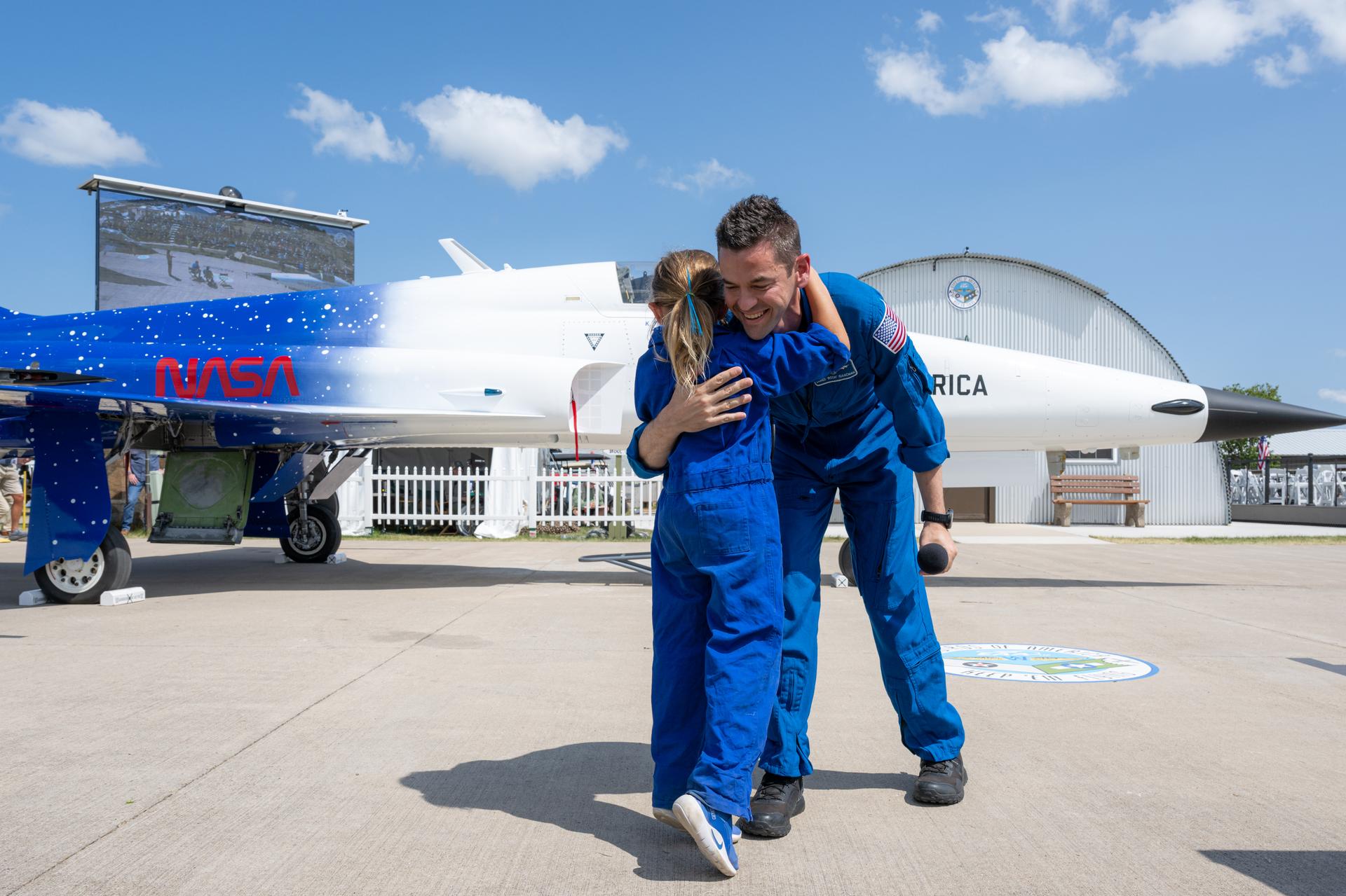 NASA Administrator Jared Isaacman hugs a young aviation enthusiast during a “Warbirds in Review” presentation, Thursday, July 23, 2026, at EAA AirVenture Oshkosh at Wittman Regional Airport in Oshkosh, Wis. Isaacman discussed NASA’s efforts in air and space, his aviation experience, and more. Photo Credit: (NASA/John Kraus)