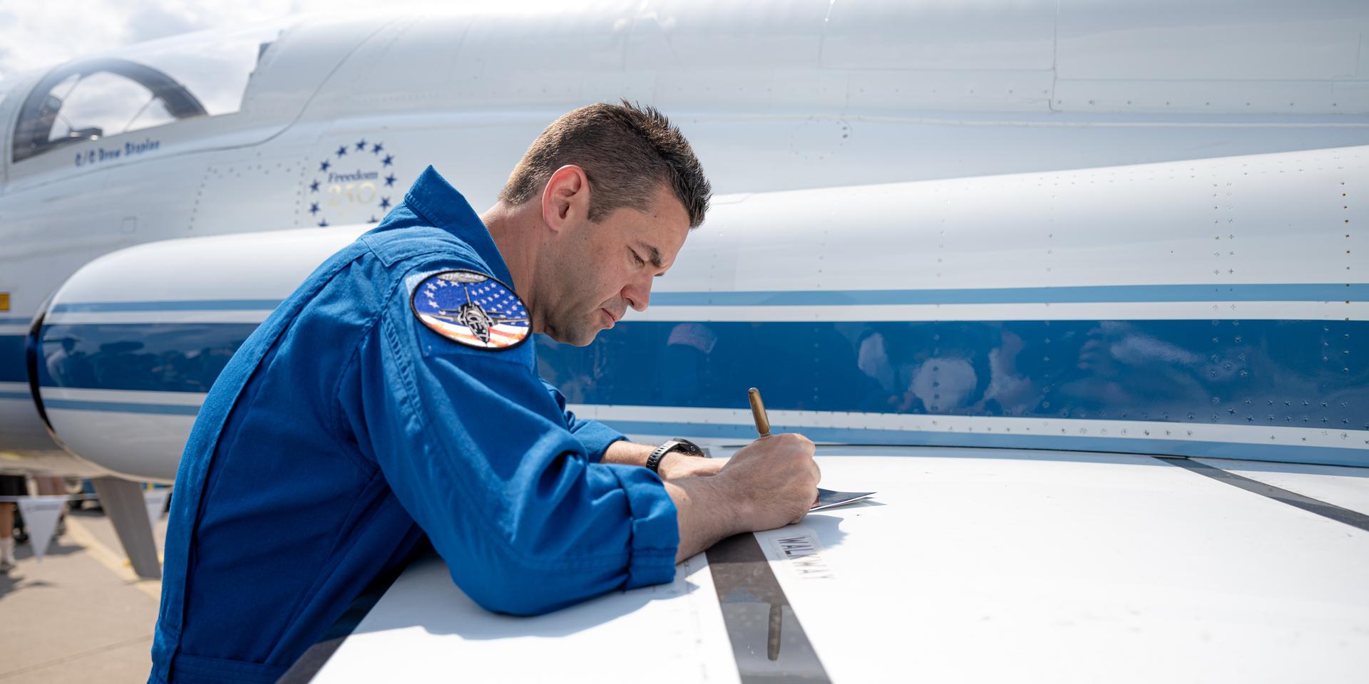 NASA Administrator Jared Isaacman signs a poster following a speaking arrangement, Friday, July 24, 2026, at EAA AirVenture Oshkosh at Wittman Regional Airport in Oshkosh, Wis. Photo Credit: (NASA/John Kraus)