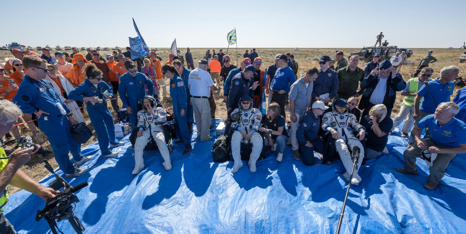 NASA astronaut Chris Williams, left, Roscosmos cosmonauts Sergey Kud-Sverchkov, center, and Sergei Mikaev, sit in chairs outside the Soyuz MS-28 spacecraft after they landed in a remote area near the town of Zhezkazgan, Kazakhstan on Sunday, July 26, 2026. The trio returned to Earth after logging 241 days in space as a members of Expeditions 73 and 74 aboard the International Space Station. Photo Credit: (NASA/Bill Ingalls)