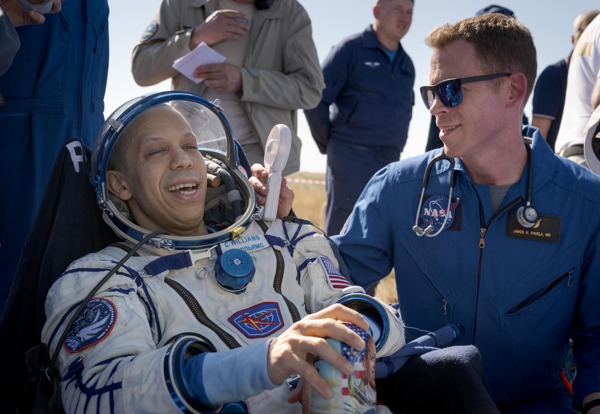 NASA astronaut Chris Williams, left, is looked after by NASA Flight Surgeon James Pavela,  outside the Soyuz MS-28 spacecraft after he landed with Roscosmos cosmonauts Sergey Kud-Sverchkov, and Sergei Mikaev in a remote area near the town of Zhezkazgan, Kazakhstan on Sunday, July 26, 2026. The trio returned to Earth after logging 241 days in space as a members of Expeditions 73 and 74 aboard the International Space Station. Photo Credit: (NASA/Bill Ingalls)