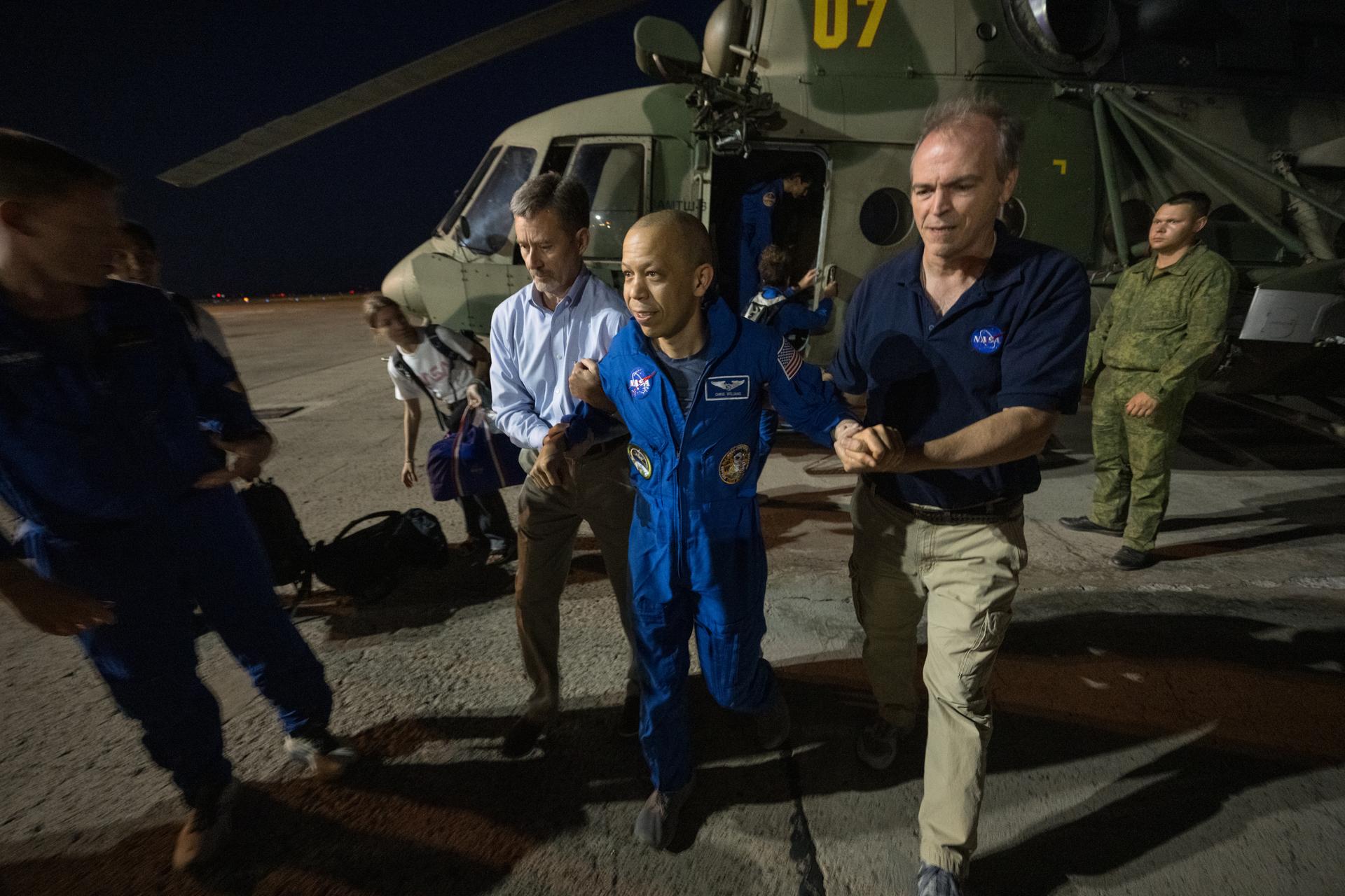 NASA astronaut Chris Williams is helped out of a helicopter by NASA Director for Human Space Flight Programs, Russia, Jay Marschke, left, and Director of Operations, Star City, Russia, John McBrine, at the Karaganda Airport in Kazakhstan after Williams, and Roscosmos cosmonauts Sergey Kud-Sverchkov, and Sergei Mikaev landed in their Soyuz MS-28 spacecraft in a remote area near the town of Zhezkazgan, Kazakhstan on Sunday, July 26, 2026. Williams, Kud-Sverchkov, and Mikaev returned to Earth after logging 241 days in space as a members of Expeditions 73 and 74 aboard the International Space Station. Photo Credit: (NASA/Bill Ingalls)