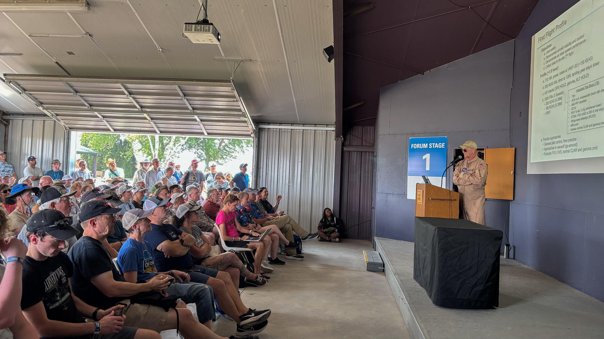 NASA test pilot Nils Larson speaks at his forum presentation “NASA’s X-59 Flight Tests Kick Off!” at the 2026 Experimental Aircraft Association (EAA) AirVenture air show in Oshkosh, Wisconsin, on Monday, July 20, 2026.