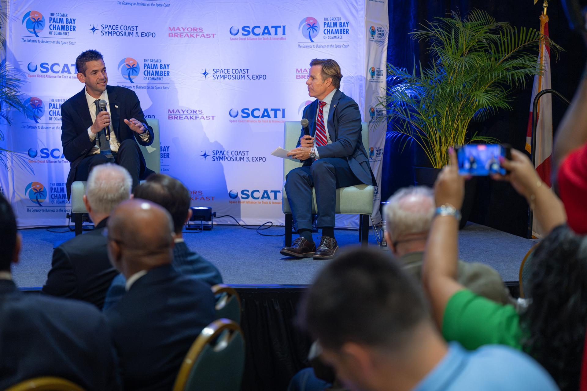 NASA Administrator Jared Isaacman, left, participates in a fireside chat with U.S. Rep. Mike Haridopolos of Florida’s 8th congressional district, right, Friday, Aug. 21, 2026, at the 8th Annual Space Coast Symposium & Expo in Cape Canaveral, Fla. Photo Credit: (NASA/John Kraus)