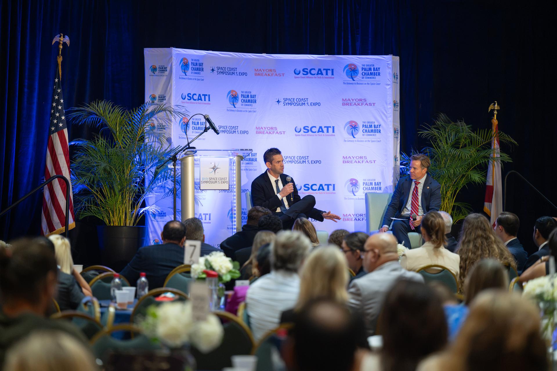 NASA Administrator Jared Isaacman, left, participates in a fireside chat with U.S. Rep. Mike Haridopolos of Florida’s 8th congressional district, right, Friday, Aug. 21, 2026, at the 8th Annual Space Coast Symposium & Expo in Cape Canaveral, Fla. Photo Credit: (NASA/John Kraus)