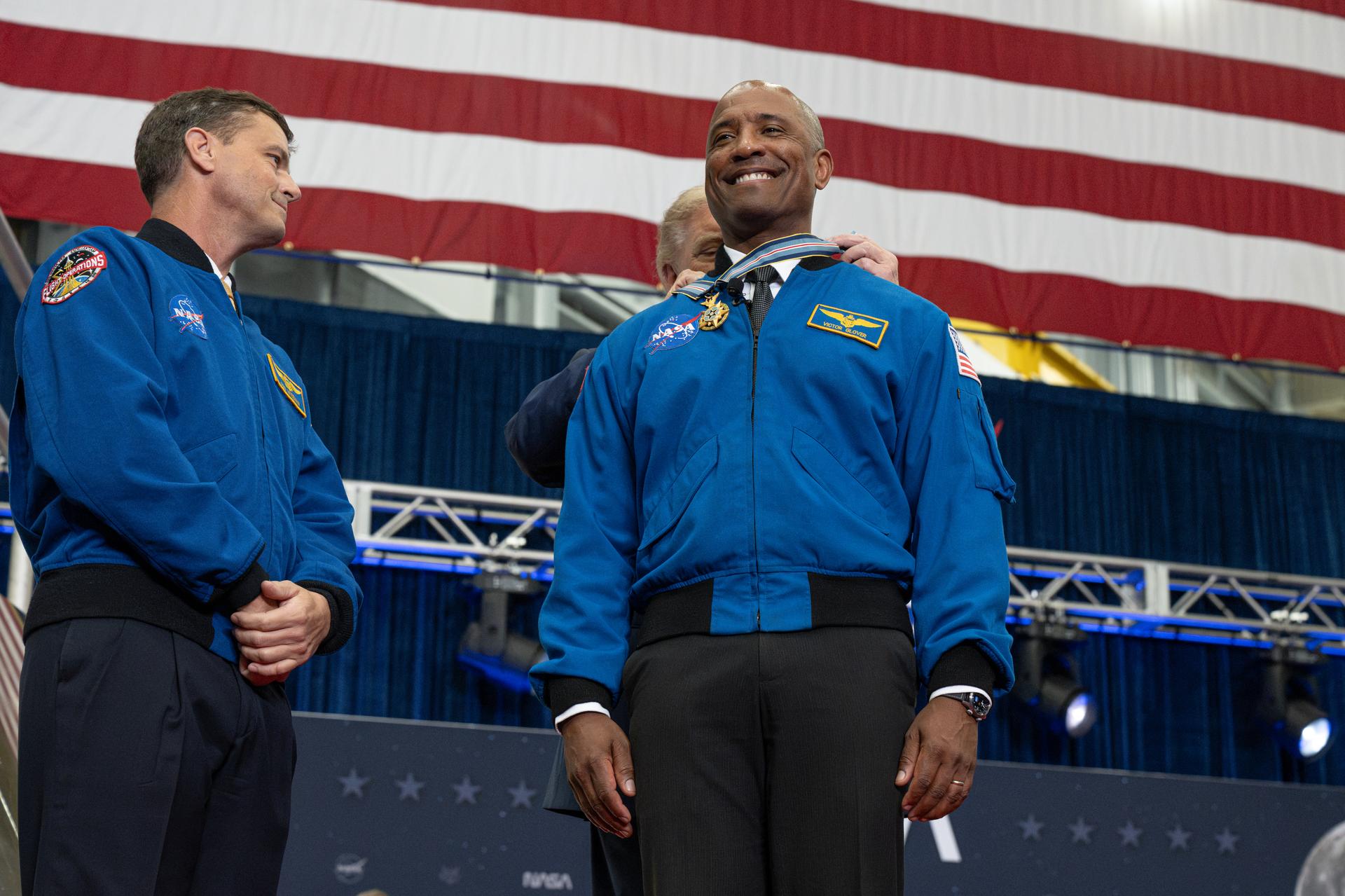 President Donald Trump awards the Congressional Space Medal of Honor to Artemis II pilot NASA astronaut Victor Glover as NASA astronaut Artemis II commander Reid Wiseman watches, Friday, Aug. 28, 2026, at NASA's Johnson Space Center in Houston, Texas. The Artemis II crew completed their approximately ten-day mission around the Moon in April 2026 and are the 31st, 32nd, 33rd, and 34th astronauts to receive the award. Photo Credit: (NASA/John Kraus)