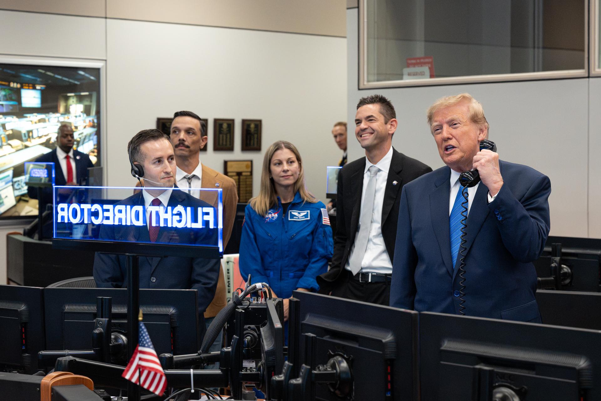 President Donald Trump speaks with Expedition 75 crewmembers Jack Hathaway, Anil Menon, and Jessica Meir on board the International Space Station during a visit to the Christopher C. Kraft Jr. Mission Control Center as NASA Administrator Jared Isaacman and Expedition 75 spouses Duke Brady and NASA astronaut candidate Anna Menon listen, Friday, Aug. 28, 2026, at NASA’s Johnson Space Center in Houston, Texas. Photo Credit: (NASA/John Kraus)