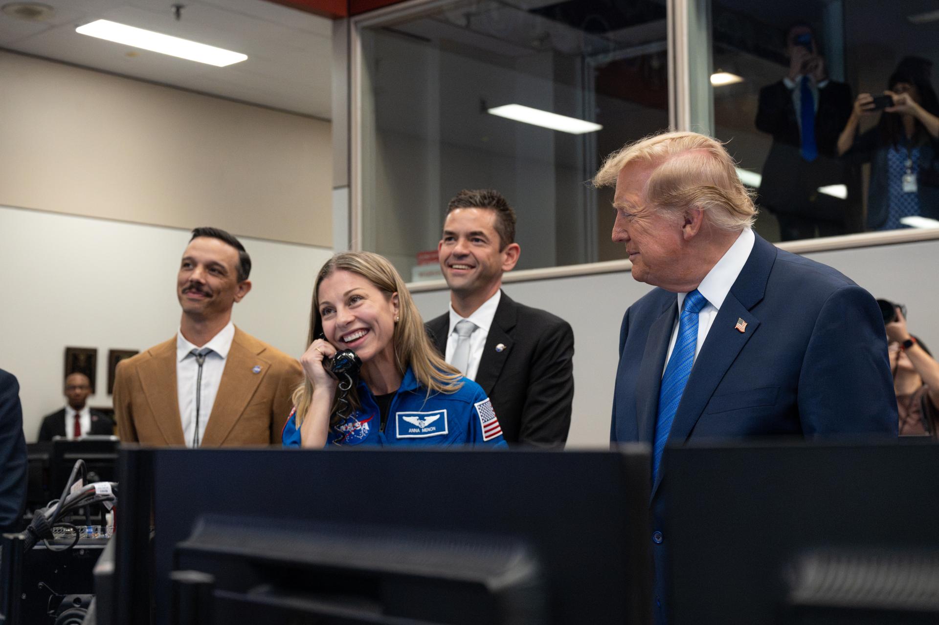 President Donald Trump, NASA Administrator Jared Isaacman, and Duke Brady, spouse of Expedition 75 crew member Jessica Meir, listen as NASA astronaut candidate Anna Menon, spouse of Expedition 75 crew member Anil Menon, speaks with Expedition 75 crewmembers Jack Hathaway, Anil Menon, and Jessica Meir on board the International Space Station during a visit to the Christopher C. Kraft Jr. Mission Control Center, Friday, Aug. 28, 2026, at NASA’s Johnson Space Center in Houston, Texas. Photo Credit: (NASA/John Kraus)