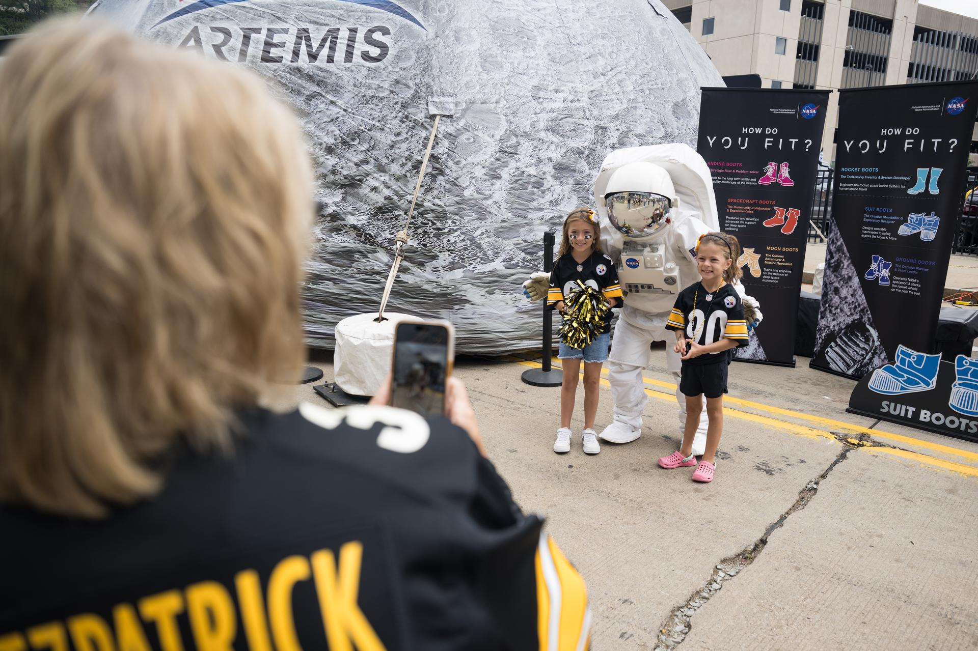 Fans pose for a photo in the NASA Experience Zone at an NFL game between the Pittsburgh Steelers and the Atlanta Falcons at Acrisure Stadium, Sunday, Sept. 13, 2026, in Pittsburgh, Pennsylvania. NASA’s engagement at NFL games is part of the agency's Inspiration Tour, aimed at strengthening connections between NASA and its partners and showcasing innovation in air and space in the lead up to the MAX POWER aerospace technology expo and airshow at the agency's Kennedy Space Center in early November. Photo Credit: (NASA/Aubrey Gemignani)