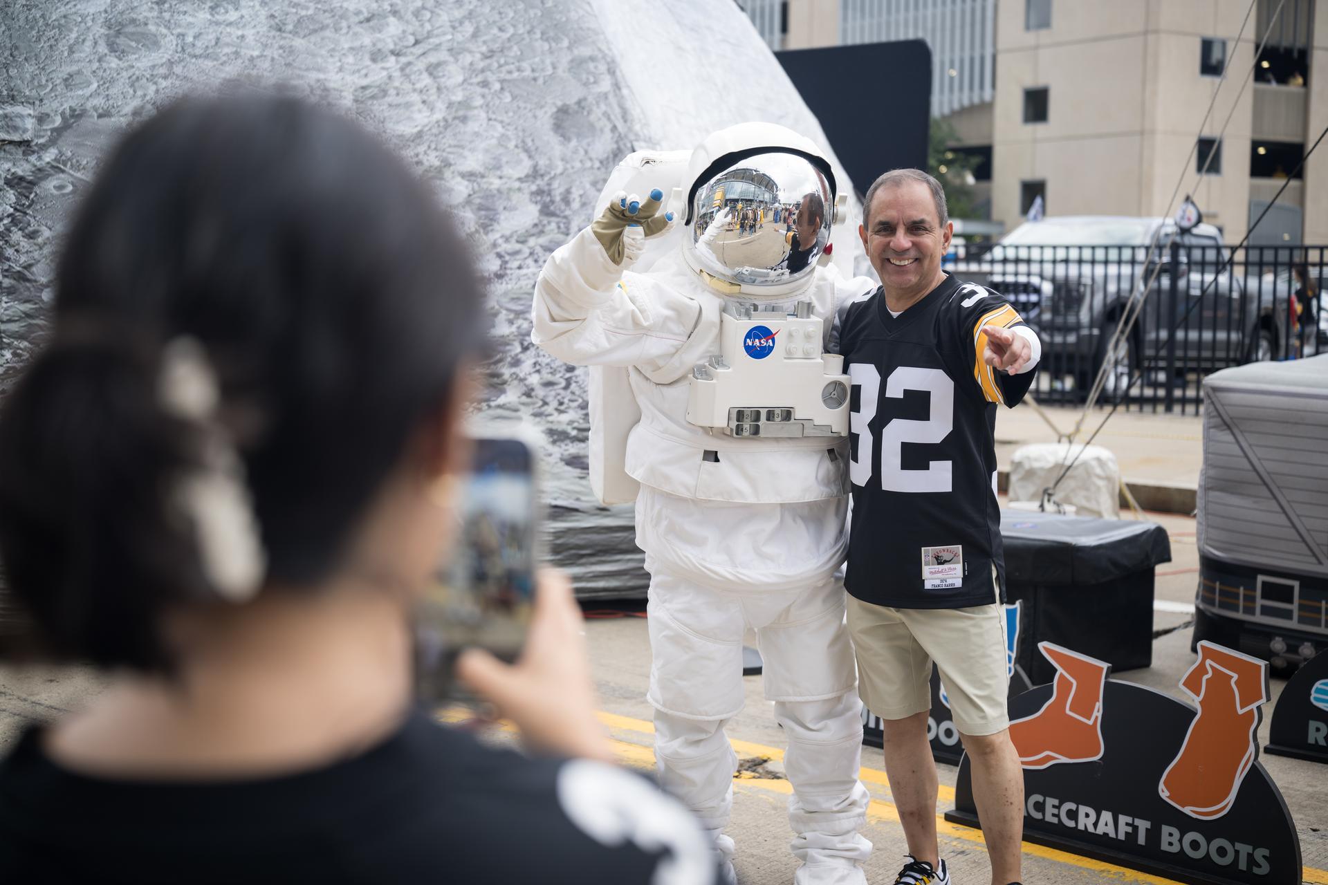 Fans pose for a photo with the astronaut in the NASA Experience Zone at an NFL game between the Pittsburgh Steelers and the Atlanta Falcons at Acrisure Stadium, Sunday, Sept. 13, 2026, in Pittsburgh, Pennsylvania. NASA’s engagement at NFL games is part of the agency's Inspiration Tour, aimed at strengthening connections between NASA and its partners and showcasing innovation in air and space in the lead up to the MAX POWER aerospace technology expo and airshow at the agency's Kennedy Space Center in early November. Photo Credit: (NASA/Aubrey Gemignani)