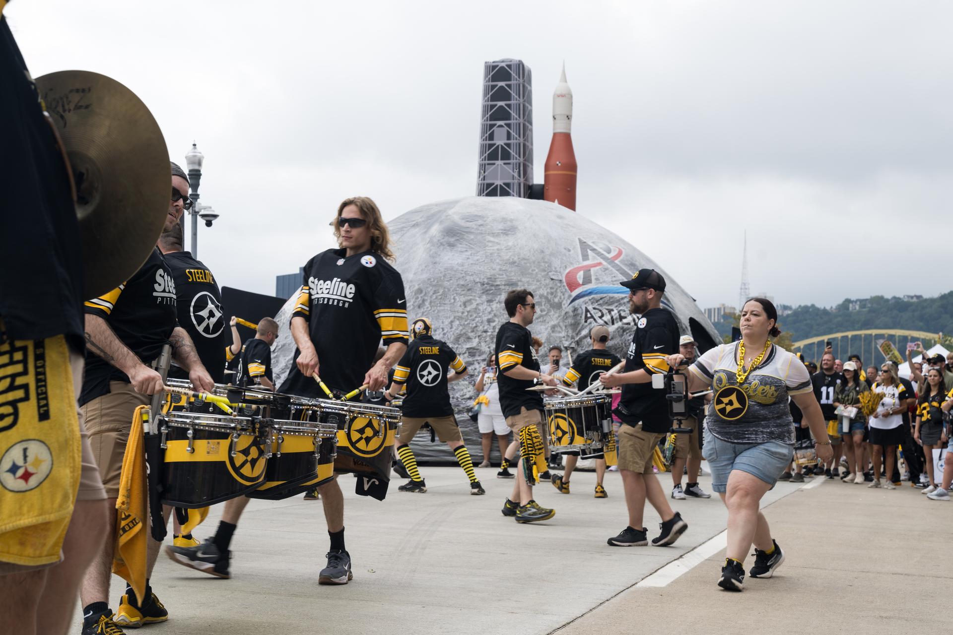 Pittsburgh Steeline, the independent, professional drumline that performs at Pittsburgh Steelers games performs in front of the NASA Experience Zone at an NFL game between the Pittsburgh Steelers and the Atlanta Falcons at Acrisure Stadium, Sunday, Sept. 13, 2026, in Pittsburgh, Pennsylvania. NASA’s engagement at NFL games is part of the agency's Inspiration Tour, aimed at strengthening connections between NASA and its partners and showcasing innovation in air and space in the lead up to the MAX POWER aerospace technology expo and airshow at the agency's Kennedy Space Center in early November. Photo Credit: (NASA/Aubrey Gemignani)