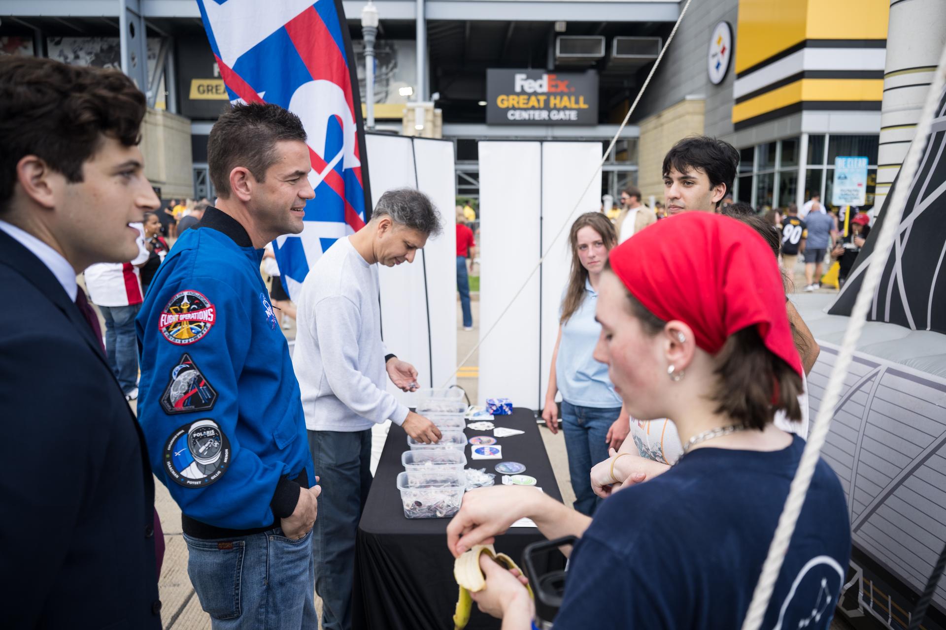 NASA Administrator Jared Isaacman speaks with student volunteers outside the NASA Experience Zone at an NFL game between the Pittsburgh Steelers and the Atlanta Falcons at Acrisure Stadium, Sunday, Sept. 13, 2026, in Pittsburgh, Pennsylvania. NASA’s engagement at NFL games is part of the agency's Inspiration Tour, aimed at strengthening connections between NASA and its partners and showcasing innovation in air and space in the lead up to the MAX POWER aerospace technology expo and airshow at the agency's Kennedy Space Center in early November. Photo Credit: (NASA/Aubrey Gemignani)