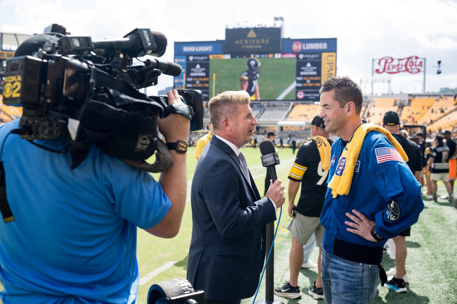 NASA Administrator Jared Isaacman is interviewed by media at an NFL game between the Pittsburgh Steelers and the Atlanta Falcons at Acrisure Stadium, Sunday, Sept. 13, 2026, in Pittsburgh, Pennsylvania. NASA’s engagement at NFL games is part of the agency's Inspiration Tour, aimed at strengthening connections between NASA and its partners and showcasing innovation in air and space in the lead up to the MAX POWER aerospace technology expo and airshow at the agency's Kennedy Space Center in early November. Photo Credit: (NASA/Aubrey Gemignani)