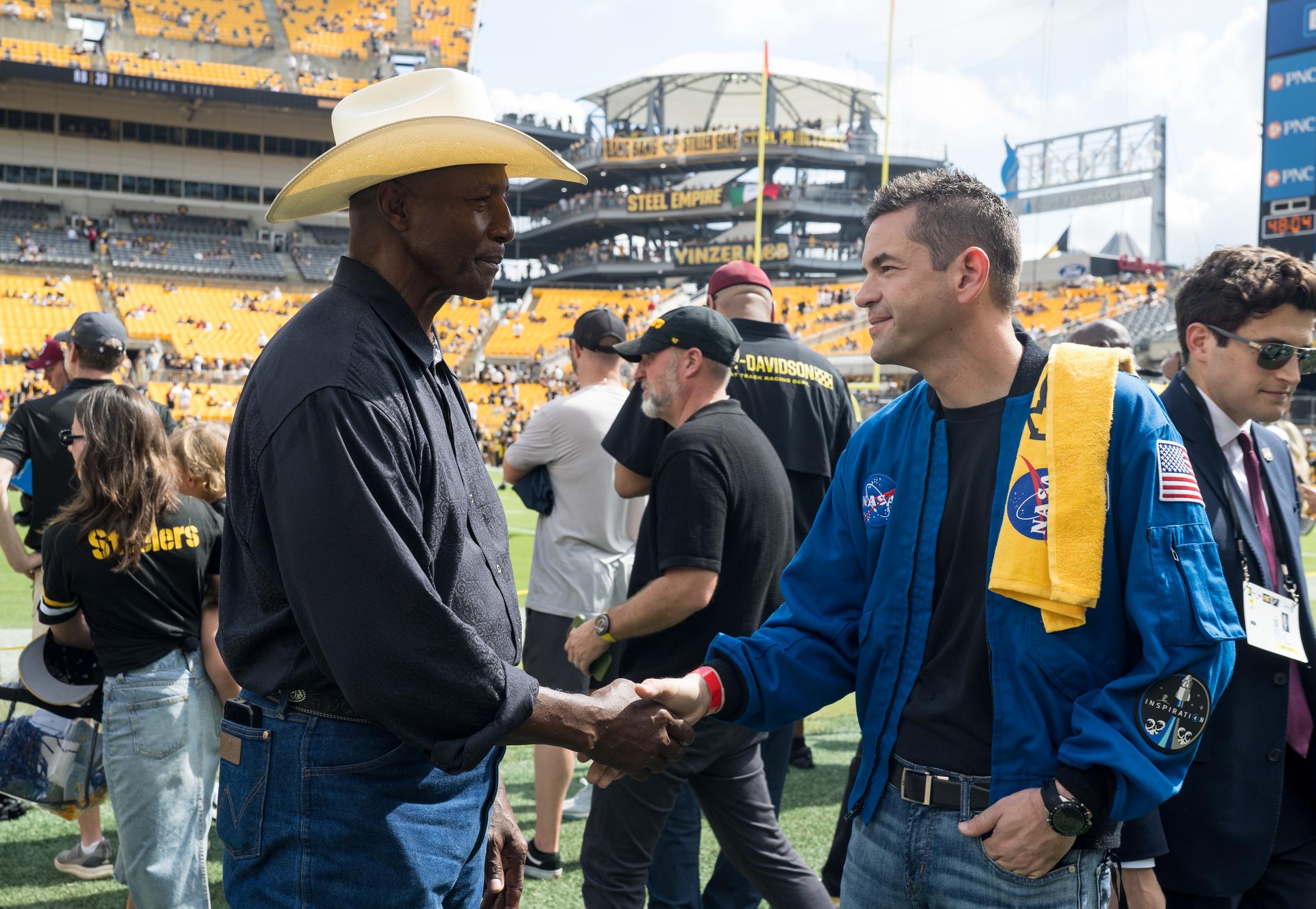 NASA Administrator Jared Isaacman right, shakes hands with Mel Blount, former Pittsburgh Steelers professional football player at an NFL game between the Pittsburgh Steelers and the Atlanta Falcons at Acrisure Stadium, Sunday, Sept. 13, 2026, in Pittsburgh, Pennsylvania. NASA’s engagement at NFL games is part of the agency's Inspiration Tour, aimed at strengthening connections between NASA and its partners and showcasing innovation in air and space in the lead up to the MAX POWER aerospace technology expo and airshow at the agency's Kennedy Space Center in early November. Photo Credit: (NASA/Aubrey Gemignani)