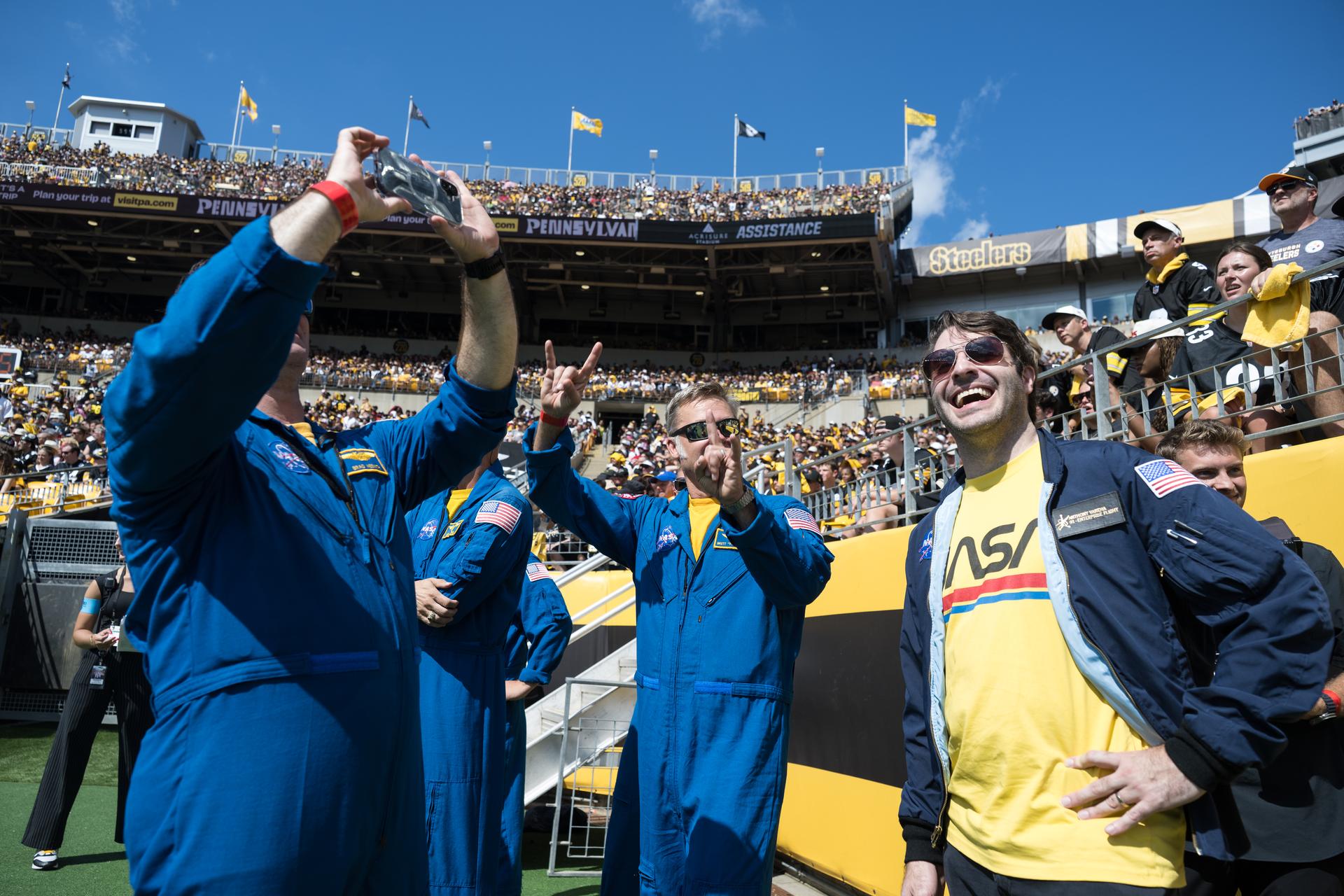 NASA Flight Director Anthony Vareha, right, waits on the field with the flyover team, pilots Brett Pugsley, Chris Condon, and co-pilot Geoff Palmer, as well as NASA Ground Liaison Brad Nesmith and Rufus Brennemen before they are featured on the Jumbotron at an NFL game between the Pittsburgh Steelers and the Atlanta Falcons at Acrisure Stadium, Sunday, Sept. 13, 2026, in Pittsburgh, Pennsylvania. NASA’s engagement at NFL games is part of the agency's Inspiration Tour, aimed at strengthening connections between NASA and its partners and showcasing innovation in air and space in the lead up to the MAX POWER aerospace technology expo and airshow at the agency's Kennedy Space Center in early November. Photo Credit: (NASA/Aubrey Gemignani)