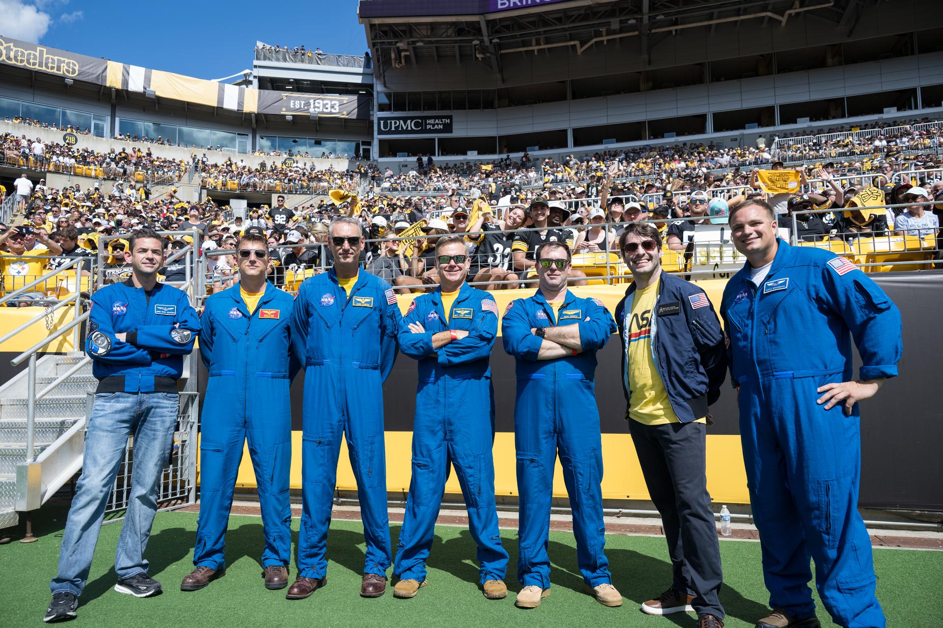 From left to right, NASA Administrator Jared Isaacman, Geoff Palmer, NASA Co-Pilot, Chris Condon, NASA Wing Pilot, Brett Pugsley, NASA Lead Pilot, Brad Nesmith, NASA Ground Liaison, Anthony Vareha, NASA Flight Director, and Rufus Brennemen, NASA Ground Liaison pose for a photo before they participate in a call back on the sidelines after conducting a flyover at an NFL game between the Pittsburgh Steelers and the Atlanta Falcons at Acrisure Stadium, Sunday, Sept. 13, 2026, in Pittsburgh, Pennsylvania. NASA’s engagement at NFL games is part of the agency's Inspiration Tour, aimed at strengthening connections between NASA and its partners and showcasing innovation in air and space in the lead up to the MAX POWER aerospace technology expo and airshow at the agency's Kennedy Space Center in early November. Photo Credit: (NASA/Aubrey Gemignani)