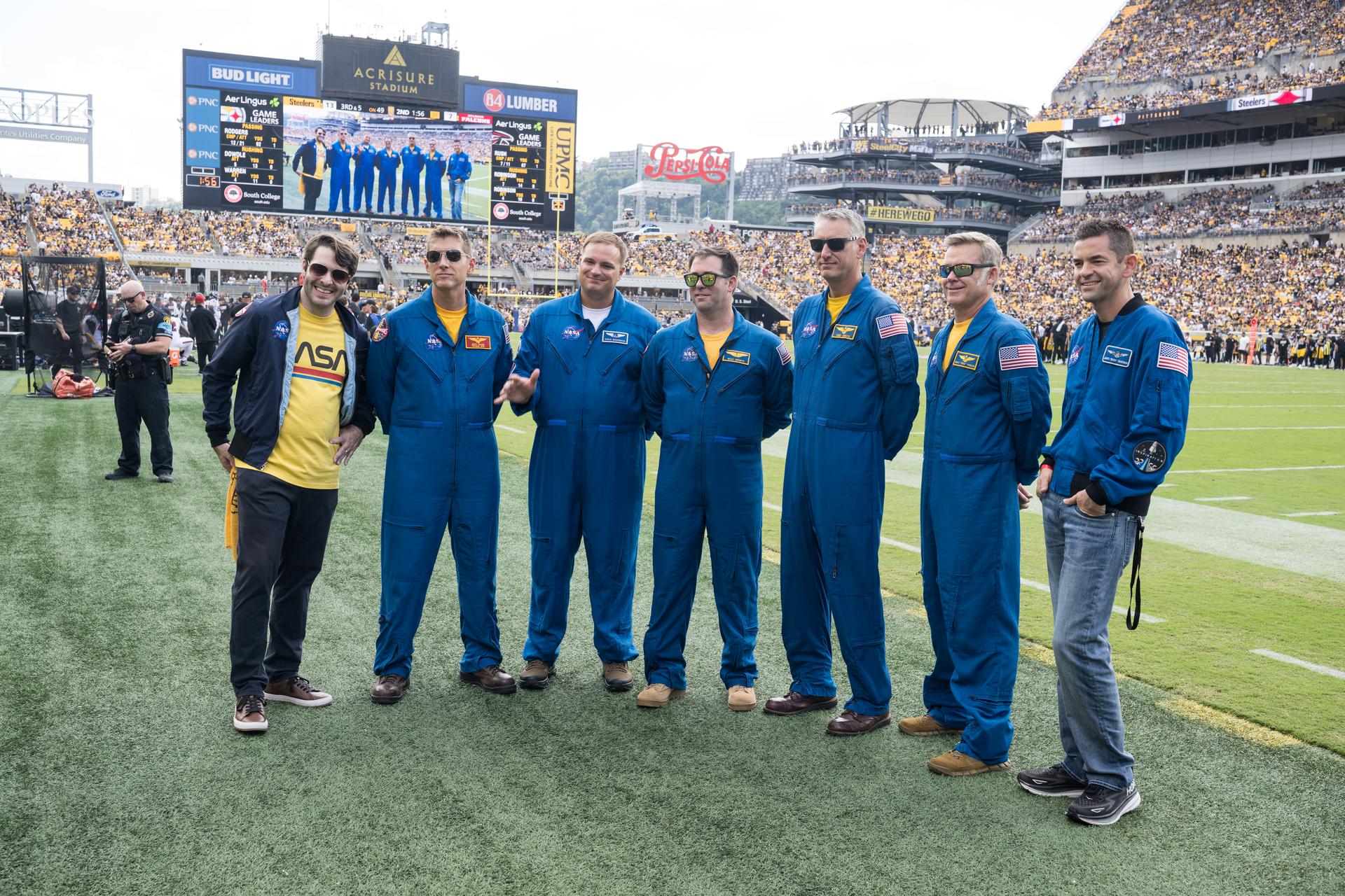From left to right, Anthony Vareha, NASA Flight Director, Geoff Palmer, NASA Co-Pilot, Rufus Brennemen, NASA Ground Liaison, Brad Nesmith, NASA Ground Liaison, Chris Condon, NASA Wing Pilot, Brett Pugsley, NASA Lead Pilot, and NASA Administrator Jared Isaacman are seen on the Jumbotron as they participate in a call back after Pugsley, Condon, and Palmer conducted a flyover at an NFL game between the Pittsburgh Steelers and the Atlanta Falcons at Acrisure Stadium, Sunday, Sept. 13, 2026, in Pittsburgh, Pennsylvania. NASA’s engagement at NFL games is part of the agency's Inspiration Tour, aimed at strengthening connections between NASA and its partners and showcasing innovation in air and space in the lead up to the MAX POWER aerospace technology expo and airshow at the agency's Kennedy Space Center in early November. Photo Credit: (NASA/Aubrey Gemignani)