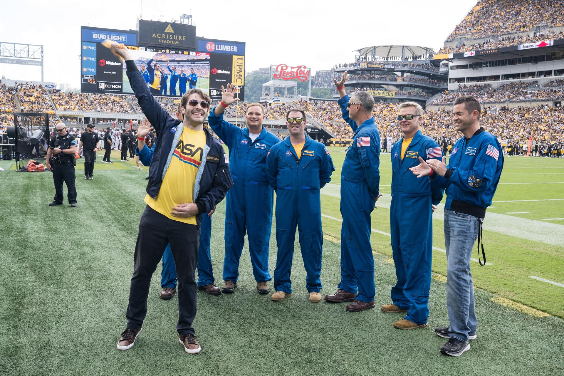 From left to right, Anthony Vareha, NASA Flight Director, Geoff Palmer (behind Vareha), NASA Co-Pilot, Rufus Brennemen, NASA Ground Liaison, Brad Nesmith, NASA Ground Liaison, Chris Condon, NASA Wing Pilot, Brett Pugsley, NASA Lead Pilot, and NASA Administrator Jared Isaacman are seen on the Jumbotron as they participate in a call back after Pugsley, Condon, and Palmer conducted a flyover at an NFL game between the Pittsburgh Steelers and the Atlanta Falcons at Acrisure Stadium, Sunday, Sept. 13, 2026, in Pittsburgh, Pennsylvania. NASA’s engagement at NFL games is part of the agency's Inspiration Tour, aimed at strengthening connections between NASA and its partners and showcasing innovation in air and space in the lead up to the MAX POWER aerospace technology expo and airshow at the agency's Kennedy Space Center in early November. Photo Credit: (NASA/Aubrey Gemignani)