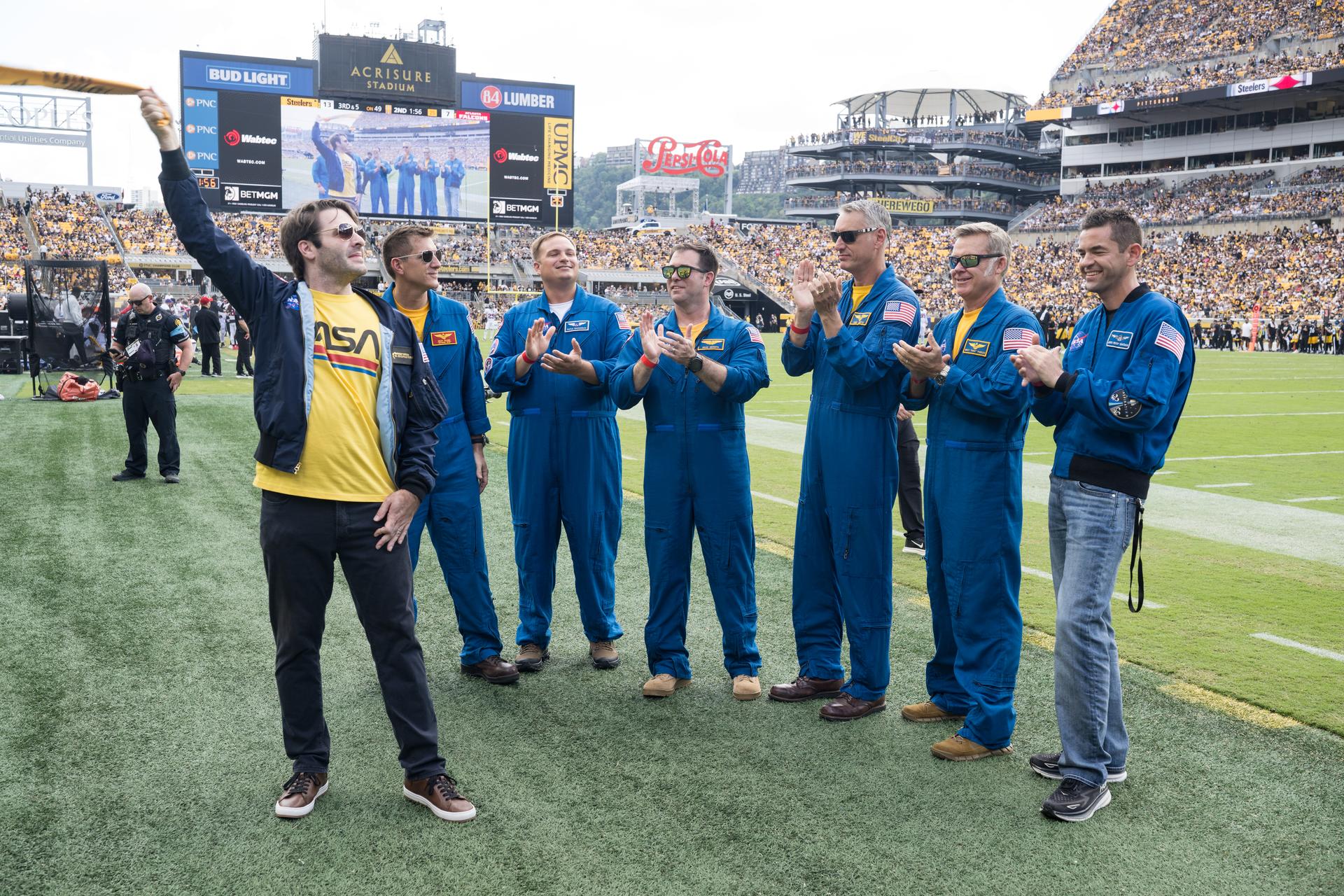 From left to right, Anthony Vareha, NASA Flight Director, Geoff Palmer, NASA Co-Pilot, Rufus Brennemen, NASA Ground Liaison, Brad Nesmith, NASA Ground Liaison, Chris Condon, NASA Wing Pilot, Brett Pugsley, NASA Lead Pilot, and NASA Administrator Jared Isaacman are seen on the Jumbotron as they participate in a call back after Pugsley, Condon, and Palmer conducted a flyover at an NFL game between the Pittsburgh Steelers and the Atlanta Falcons at Acrisure Stadium, Sunday, Sept. 13, 2026, in Pittsburgh, Pennsylvania. NASA’s engagement at NFL games is part of the agency's Inspiration Tour, aimed at strengthening connections between NASA and its partners and showcasing innovation in air and space in the lead up to the MAX POWER aerospace technology expo and airshow at the agency's Kennedy Space Center in early November. Photo Credit: (NASA/Aubrey Gemignani)