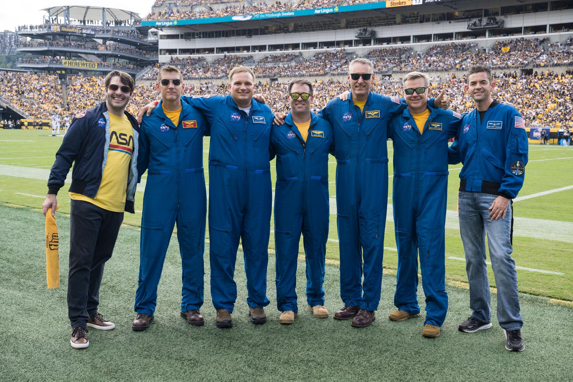 From left to right, Anthony Vareha, NASA Flight Director, Geoff Palmer, NASA Co-Pilot, Rufus Brennemen, NASA Ground Liaison, Brad Nesmith, NASA Ground Liaison, Chris Condon, NASA Wing Pilot, Brett Pugsley, NASA Lead Pilot, and NASA Administrator Jared Isaacman pose for a photo after they participated in a call back after Pugsley, Condon, and Palmer conducted a flyover at an NFL game between the Pittsburgh Steelers and the Atlanta Falcons at Acrisure Stadium, Sunday, Sept. 13, 2026, in Pittsburgh, Pennsylvania. NASA’s engagement at NFL games is part of the agency's Inspiration Tour, aimed at strengthening connections between NASA and its partners and showcasing innovation in air and space in the lead up to the MAX POWER aerospace technology expo and airshow at the agency's Kennedy Space Center in early November. Photo Credit: (NASA/Aubrey Gemignani)
