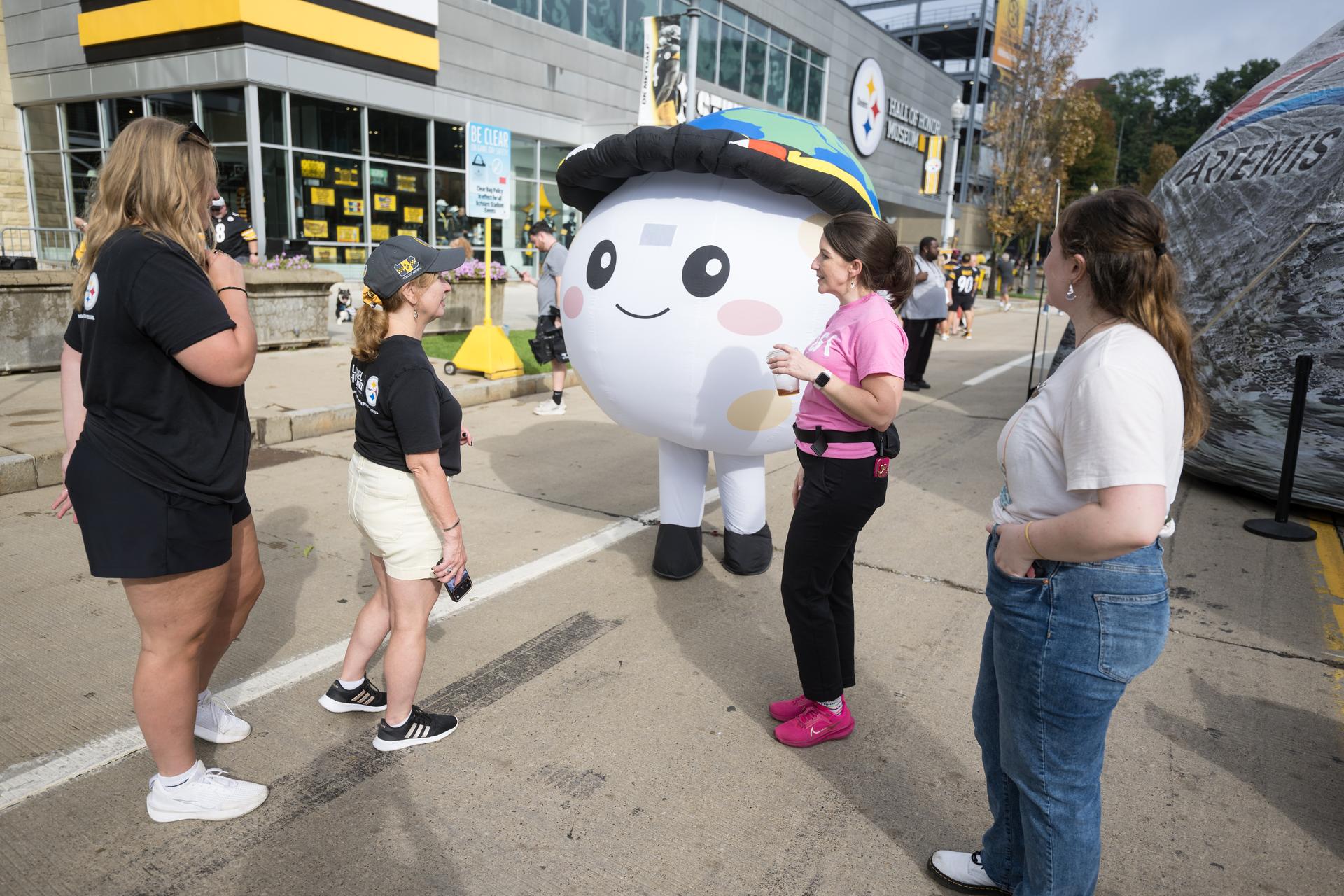 Kristen Parker, NASA communications liaison, second from right, stands next to Rise, the zero gravity indicator from the Artemis II mission and greets fans in the NASA Experience Zone at an NFL game between the Pittsburgh Steelers and the Atlanta Falcons at Acrisure Stadium, Sunday, Sept. 13, 2026, in Pittsburgh, Pennsylvania. NASA’s engagement at NFL games is part of the agency's Inspiration Tour, aimed at strengthening connections between NASA and its partners and showcasing innovation in air and space in the lead up to the MAX POWER aerospace technology expo and airshow at the agency's Kennedy Space Center in early November. Photo Credit: (NASA/Aubrey Gemignani)