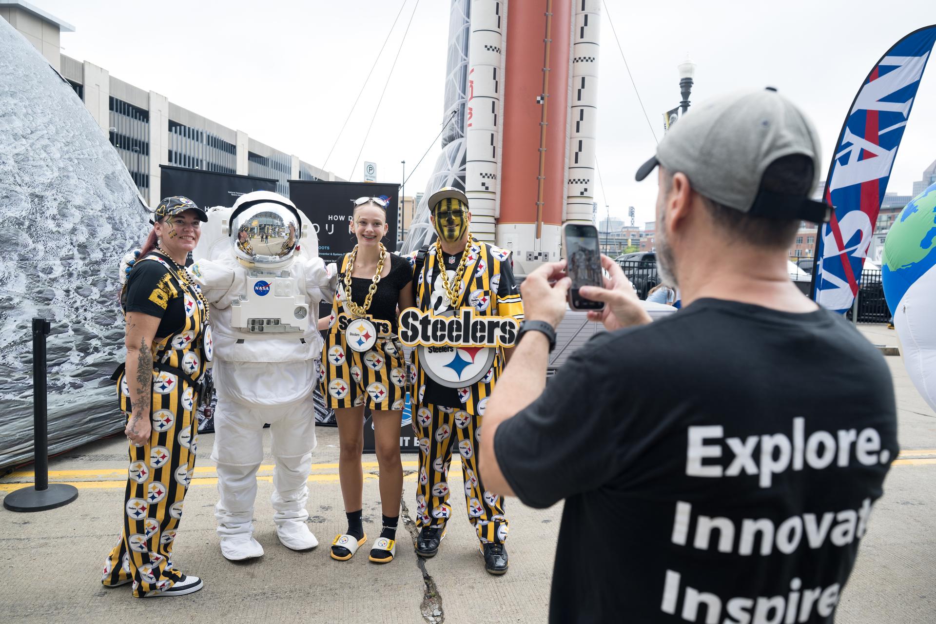 Fans pose for a photo with an astronaut in the NASA Experience Zone at an NFL game between the Pittsburgh Steelers and the Atlanta Falcons at Acrisure Stadium, Sunday, Sept. 13, 2026, in Pittsburgh, Pennsylvania. NASA’s engagement at NFL games is part of the agency's Inspiration Tour, aimed at strengthening connections between NASA and its partners and showcasing innovation in air and space in the lead up to the MAX POWER aerospace technology expo and airshow at the agency's Kennedy Space Center in early November. Photo Credit: (NASA/Aubrey Gemignani)