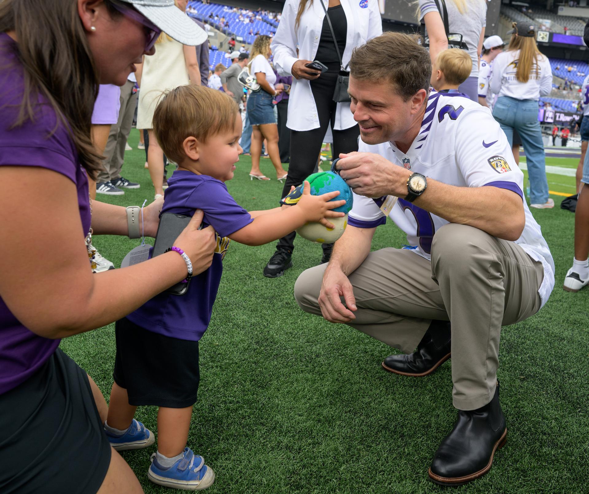 NASA astronaut and commander of the agency’s Artemis II mission, Reid Wiseman, a Baltimore native, shows a young fan Rise, the zero gravity indicator from the Artemis II mission, at an NFL game between the New Orleans Saints and the Baltimore Ravens at M&T Bank Stadium, Sunday, Sept. 20, 2026, in Baltimore. NASA’s engagement at NFL games is part of the agency's Inspiration Tour, aimed at strengthening connections between NASA and its partners and showcasing innovation in air and space in the lead up to the MAX POWER aerospace technology expo and airshow at the agency's Kennedy Space Center in early November. Photo Credit: (NASA/Bill Ingalls)