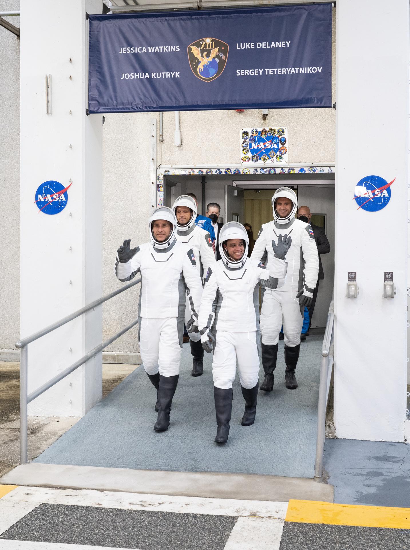 NASA astronauts Luke Delaney, front left, and Jessica Watkins, front right, CSA (Canadian Space Agency) astronaut Joshua Kutryk, back left, and Roscosmos cosmonaut Sergey Teteryatnikov, back right, wearing SpaceX spacesuits, are seen as they prepare to depart the Neil  A. Armstrong Operations and Checkout Building for Space Launch Complex 40 on Cape Canaveral Space Force Station to board the SpaceX Dragon spacecraft for the Crew-13 mission launch, Thursday, Oct. 1, 2026, at NASA’s Kennedy Space Center in Florida. NASA’s SpaceX Crew-13 mission is the 13th crew rotation mission of the SpaceX Dragon spacecraft and Falcon 9 rocket to the International Space Station as part of the agency’s Commercial Crew Program. Watkins, Delaney, Kutryk, Teteryatnikov are scheduled to launch at 11:10 a.m. EDT, from Space Launch Complex 40 at the Cape Canaveral Space Force Station.  Photo Credit: (NASA/Joel Kowsky)