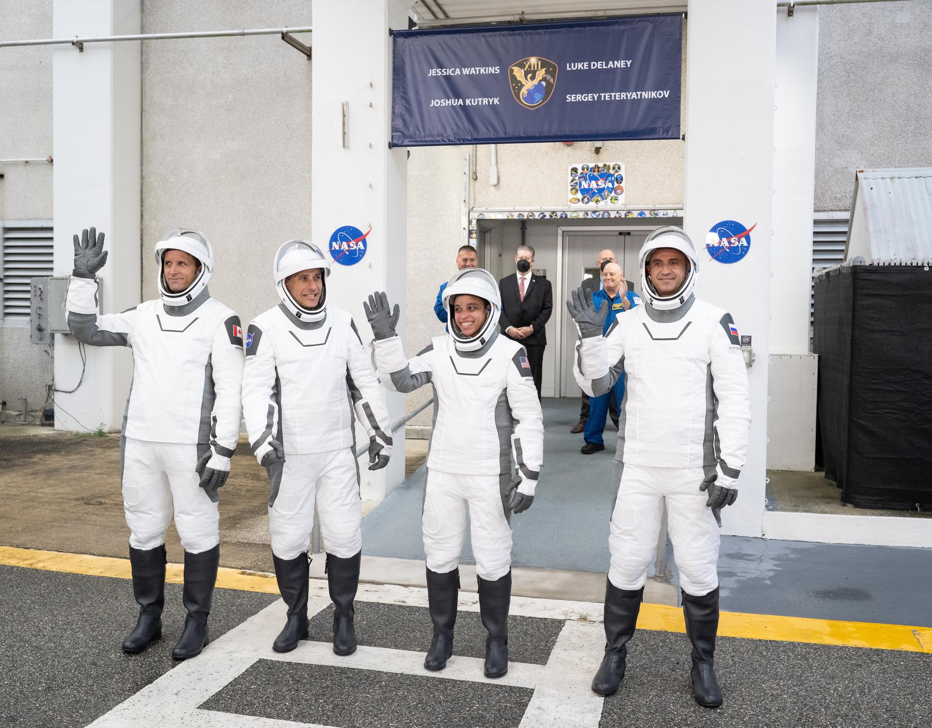 CSA (Canadian Space Agency) astronaut Joshua Kutryk, left, NASA astronauts Luke Delaney and Jessica Watkins, and Roscosmos cosmonaut Sergey Teteryatnikov, wearing SpaceX spacesuits, are seen as they prepare to depart the Neil  A. Armstrong Operations and Checkout Building for Space Launch Complex 40 on Cape Canaveral Space Force Station to board the SpaceX Dragon spacecraft for the Crew-13 mission launch, Thursday, Oct. 1, 2026, at NASA’s Kennedy Space Center in Florida. NASA’s SpaceX Crew-13 mission is the 13th crew rotation mission of the SpaceX Dragon spacecraft and Falcon 9 rocket to the International Space Station as part of the agency’s Commercial Crew Program. Watkins, Delaney, Kutryk, Teteryatnikov are scheduled to launch at 11:10 a.m. EDT, from Space Launch Complex 40 at the Cape Canaveral Space Force Station.  Photo Credit: (NASA/Joel Kowsky)