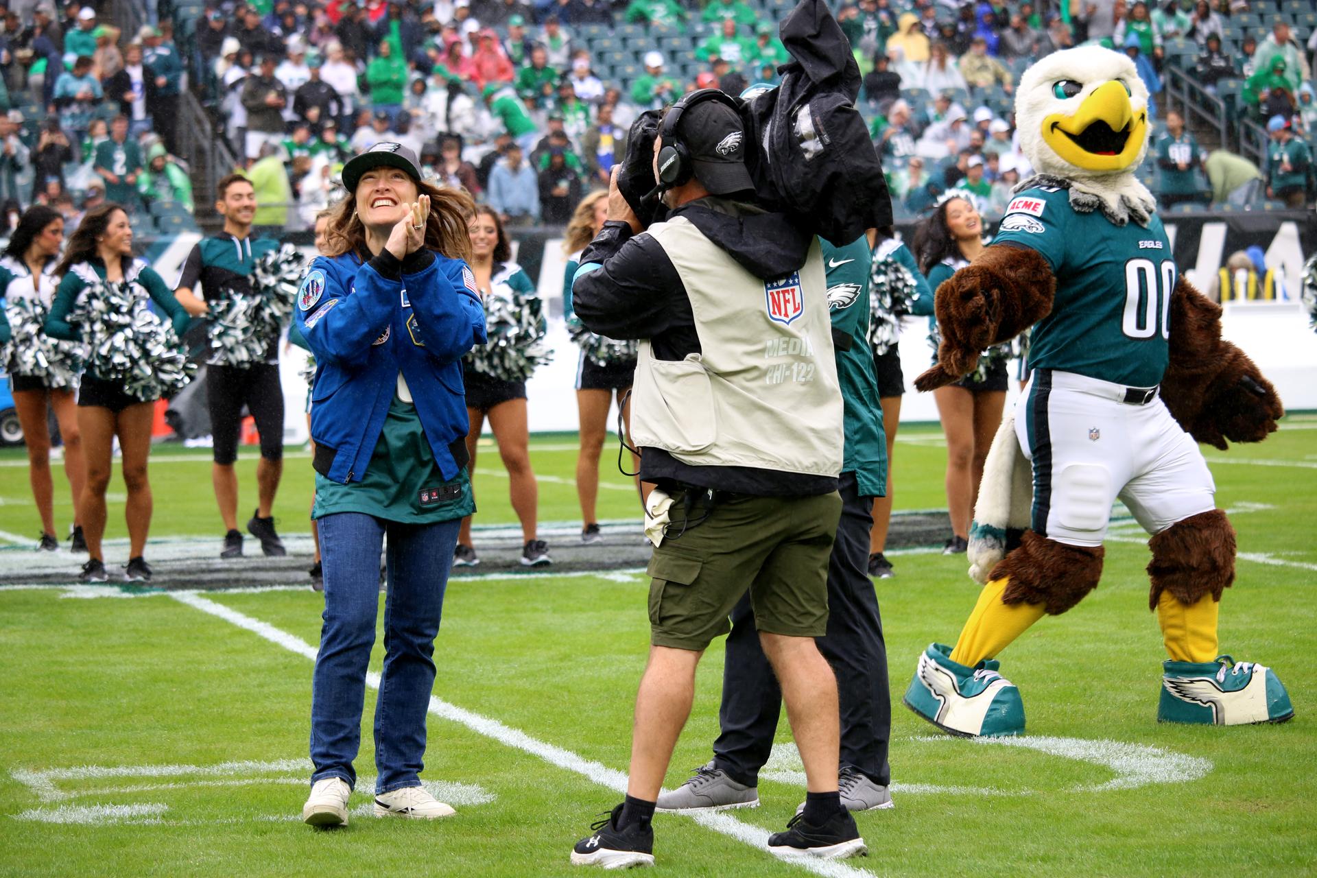 NASA astronaut and mission specialist of the agency's Artemis II mission, Christina Koch, lead the fans in singing the Eagles Fight Song from the field at an NFL game between the Philadelphia Eagles and the Los Angeles Rams at Lincoln Financial Field on Sunday, Oct. 4, 2026, in Philadelphia. NASA’s engagement at NFL games is part of the agency's Inspiration Tour, aimed at strengthening connections between NASA and its partners and showcasing innovation in air and space in the lead up to the MAX POWER aerospace technology expo and airshow at the agency's Kennedy Space Center in early November. Photo Credit: (NASA/Thalia Patrinos)