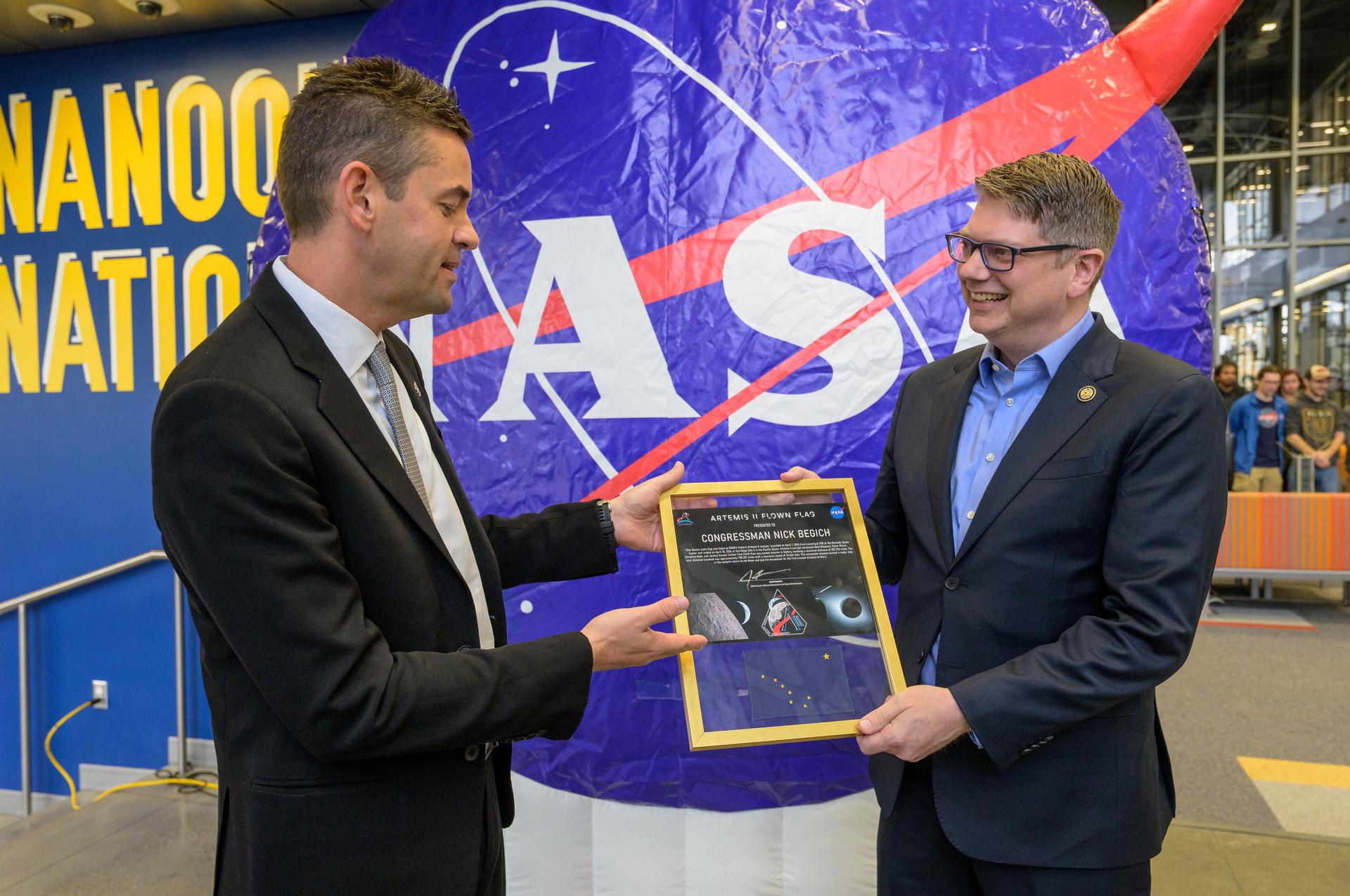 NASA Administrator Jared Isaacman, left, presents Rep. Nick Begich, R-Alaska, a plaque including an Alaska state flag that was flown on the Artemis II mission around the Moon, Monday, Oct. 5, 2026, at the University of Alaska Fairbanks, in Fairbanks, Alaska. NASA’s visit to Alaska is part of the agency's Inspiration Tour, aimed at strengthening connections between NASA and its partners and showcasing innovation in air and space in the lead up to the MAX POWER aerospace technology expo and airshow at the agency's Kennedy Space Center in early November. Photo Credit: (NASA/Bill Ingalls)