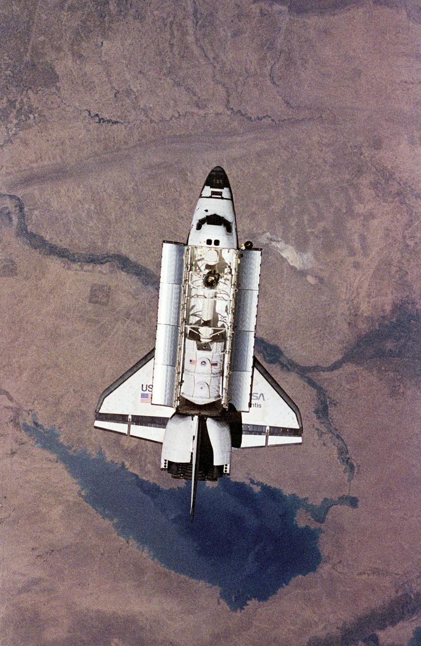 NM18-309-018 (28 June 1995) --- The Space Shuttle Atlantis orbits Earth at a point above Iraq as photographed by one of the Mir-18 crew members aboard Russia's Mir Space Station. The image was photographed prior to rendezvous and docking of the two spacecraft. The Spacelab science module and the tunnel connecting it to the crew cabin, as well as the added mechanism for interface with the Mir's docking system can be easily seen. The geography pictured is 60 miles northwest of Baghdad. The Buhayrat Ath Tharthar (reservoir) is the widest body of water visible. Also seen are the Tigris and Euphrates Rivers.