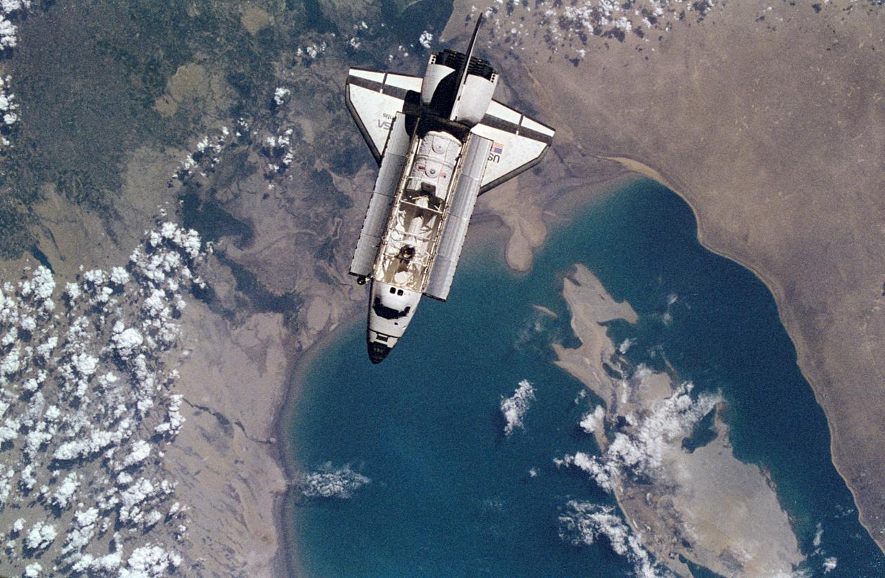 NM18-309-021 (28 June 1995) --- The Space Shuttle Atlantis orbits Earth at a point above Uzbekistan and the southern Aral Sea, as photographed by one of the Mir-18 crew members aboard Russia's Mir Space Station. The image was photographed prior to rendezvous and docking of the two spacecraft. The Spacelab Science Module and the tunnel connecting it to the crew cabin, as well as the added mechanism for interface with the Mir's docking system can be easily seen in the photo.