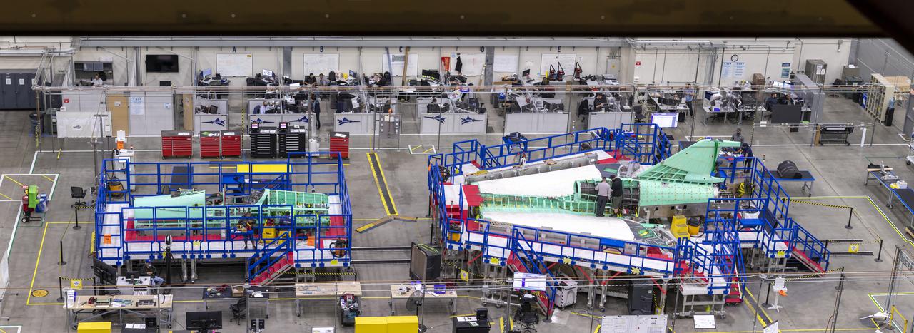This overhead shot of the X-59 Quiet SuperSonic Technology or QueSST aircraft shows the assembly progress of the vehicle during Spring 2021. In the left side of the picture, the fuselage which contains the cockpit is shown and the right side of the photo shows the wing and the tail section of the aircraft.  Lockheed Martin Photography By Garry Tice 1011 Lockheed Way, Palmdale, Ca. 93599 Event: Manufacture Area From Above Date: 3/30/2021