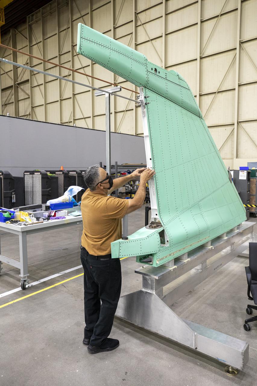 A technician is shown working on the X-59 vertical tail prior to installation at Lockheed Martin Skunk Works in Palmdale, California. The aircraft will fly to demonstrate the ability to fly supersonic while reducing the loud sonic boom to a quiet sonic thump.    Lockheed Martin Photography By Garry Tice 1011 Lockheed Way, Palmdale, Ca. 93599 Event: SEG 530 Vertical Tail, Landing Gear Bay Doors Date: 4/28/2021