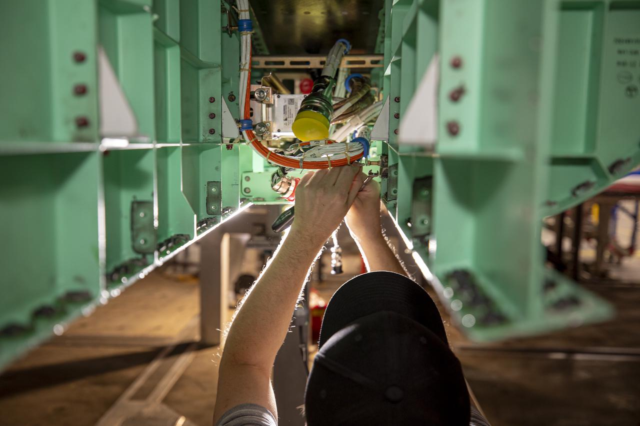 A technician is shown working on the underside of the X-59. The aircraft, under construction at Lockheed Martin Skunk Works in Palmdale, California, will fly to demonstrate the ability to fly supersonic while reducing the loud sonic boom to a quiet sonic thump.  Lockheed Martin Photography By Garry Tice 1011 Lockheed Way, Palmdale, Ca. 93599 Event: SEG 450 Mid Bay - PDS Fit Check Date: 5/03/2021