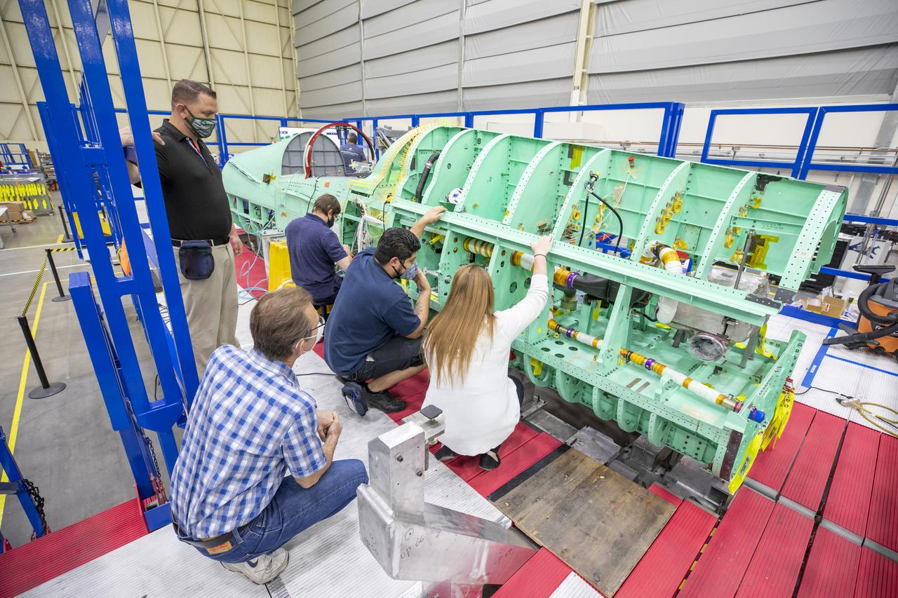 Technicians are shown here working on the X-59 fuselage section of the aircraft.  The fuselage contains the cockpit and helps define the distinct shape of the X-59.  Lockheed Martin Photography By Garry Tice 1011 Lockheed Way, Palmdale, Ca. 93599 Event: SEG 210 Forebody-Subsystems Date: 5/12/2021