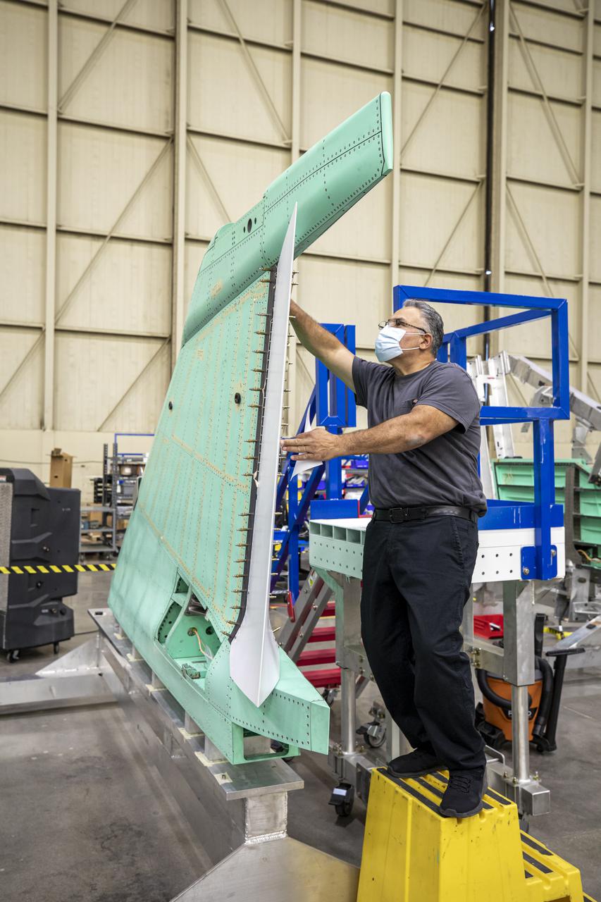 A technician is shown working on the X-59 vertical tail prior to installation. The aircraft, under construction at Lockheed Martin Skunk Works in Palmdale, California, will fly to demonstrate the ability to fly supersonic while reducing the loud sonic boom to a quiet sonic thump.  Lockheed Martin Photography By Garry Tice 1011 Lockheed Way, Palmdale, Ca. 93599 Event: SEG 530 Vertical Tail - Rudder Installed Date: 5/12/2021