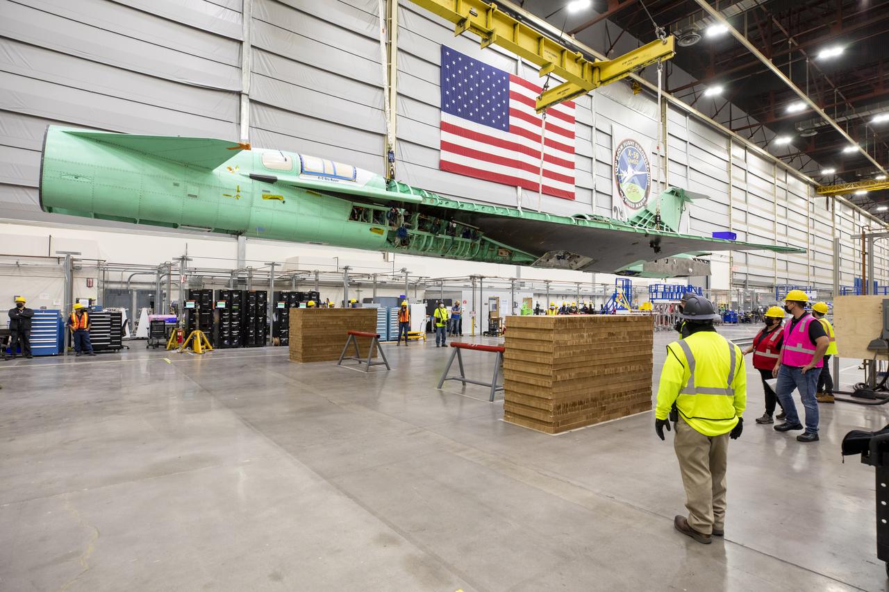 The X-59 is free from its structural support jig for the first time. In this image, cranes are holding up the aircraft prior to placement on the floor jacks. Notice that the nose has been removed temporarily  — it will be reinstalled again before the upcoming structural testing.  Lockheed Martin Photography By Garry Tice 1011 Lockheed Way, Palmdale, Ca. 93599 Event: Removal From Tooling Jig Date: 10/27/2021 Additional Info: