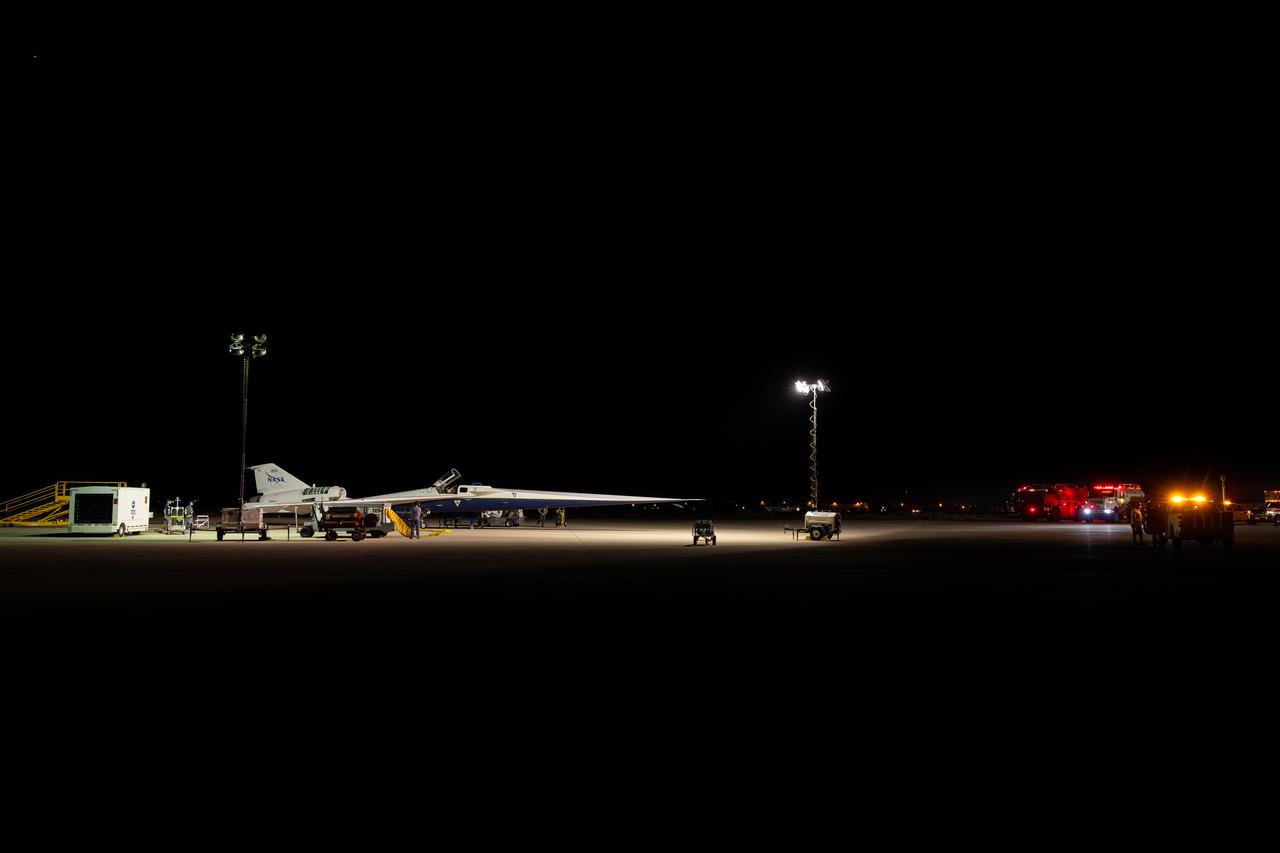 NASA’s X-59 quiet supersonic research aircraft is seen at dawn with firetrucks and safety personnel nearby during a hydrazine safety check at U.S. Air Force Plant 42 in Palmdale, California, on Aug. 18, 2025. The operation highlights the extensive precautions built into the aircraft’s safety procedures for a system that serves as a critical safeguard, ensuring the engine can be restarted in flight as the X-59 prepares for its first flight.