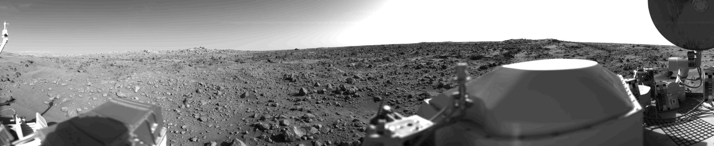 First panoramic view by NASA's Viking 1 from the surface of Mars. The out of focus spacecraft component toward left center is the housing for the Viking sample arm, which is not yet deployed. Parallel lines in the sky are an artifact and are not real features. However, the change of brightness from horizon towards zenith and towards the right (west) is accurately reflected in this picture, taken in late Martian afternoon. At the horizon to the left is a plateau-like prominence much brighter than the foreground material between the rocks. The horizon features are approximately three kilometers (1.8 miles) away. At left is a collection of fine-grained material reminiscent of sand dunes. The dark sinuous markings in left foreground are of unknown origin. Some unidentified shapes can be perceived on the hilly eminence at the horizon towards the right. A horizontal cloud stratum can be made out halfway from the horizon to the top of the picture. At left is seen the low gain antenna for receipt of commands from the Earth. The projections on or near the horizon may represent the rims distant impact craters. In right foreground are color charts for Lander camera calibration, a mirror for the Viking magnetic properties experiment and part of a grid on the top of the Lander body. At upper right is the high gain dish antenna for direct communication between landed spacecraft and Earth. Toward the right edge is an array of smooth fine-grained material which shows some hint of ripple structure and may be the beginning of a large dune field off to the right of the picture, which joins with dunes seen at the top left in this 300 degree panoramic view. Some of the rocks appear to be undercut on one side and partially buried by drifting sand on the other.  http://photojournal.jpl.nasa.gov/catalog/PIA00383