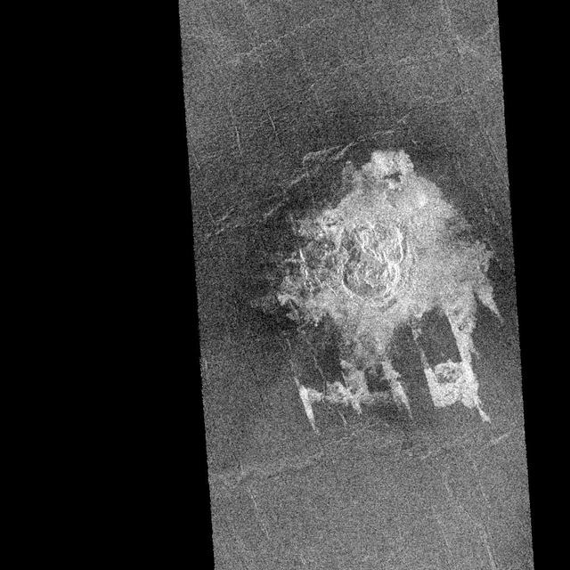NASA' sMagellan imaged this multiple-floored, irregular impact crater at latitude 16.4 degrees north, longitude 352.1 degrees east, during orbits 481 and 482 on 27 September 1990. This crater, about 9.2 kilometers in maximum diameter, was formed on what appears to be a slightly fractured, radar-dark (smooth) plain. The abundant, low viscosity flows associated with this cratering event have, however, filled local, fault-controlled troughs (called graben). These shallow graben are well portrayed on this Magellan image but would be unrecognizable but for their coincidental infilling by the radar-bright crater flows. This fortuitous enhancement by the crater flows of fault structures that are below the resolution of the Magellan synthetic aperture radar is providing the Magellan Science Team with valuable geologic information. The flow deposits from the craters are thought to consist primarily of shock melted rock and fragmented debris resulting from the nearly simultaneous impacts of two projectile fragments into the hot (800 degrees Fahrenheit) surface rocks of Venus. The presence of the various floors of this irregular crater is interpreted to be the result of crushing, fragmentation, and eventual aerodynamic dispersion of a single entry projectile during passage through the dense Venusian atmosphere. http://photojournal.jpl.nasa.gov/catalog/PIA00462