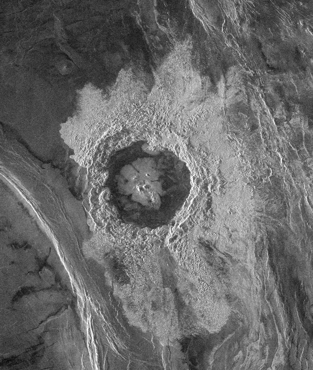This Magellan image is centered at 74.6 degrees north latitude and 177.3 east longitude, in the northeastern Atalanta Region of Venus. The image is approximately 185 kilometers (115 miles) wide at the base and shows Dickinson, an impact crater 69 kilometers (43 miles) in diameter. The crater is complex, characterized by a partial central ring and a floor flooded by radar-dark and radar-bright materials. Hummocky, rough-textured ejecta extend all around the crater, except to the west. The lack of ejecta to the west may indicate that the impactor that produced the crater was an oblique impact from the west. Extensive radar-bright flows that emanate from the crater's eastern walls may represent large volumes of impact melt, or they may be the result of volcanic material released from the subsurface during the cratering event.   http://photojournal.jpl.nasa.gov/catalog/PIA00479