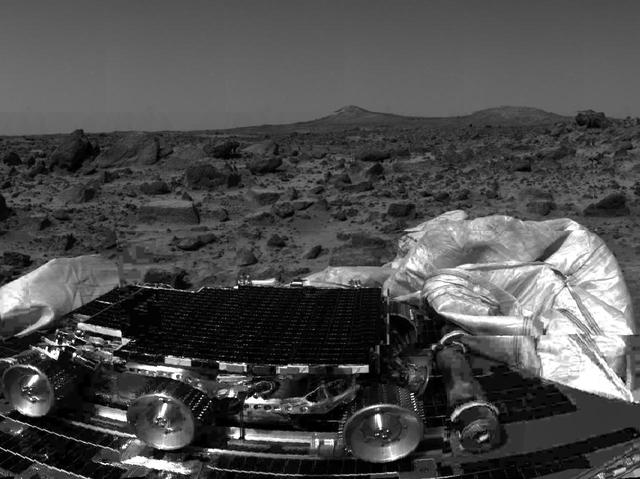 The undeployed Sojourner rover is seen still latched to a lander petal in this image, taken by the Imager for Mars Pathfinder (IMP) on Sol 1, the lander's first day on Mars. Portions of a petal and deflated airbag are in the foreground. The rectangular rock at right has been dubbed "Flat top," and may be a possible object of study for Sojourner's Alpha Proton X-Ray Spectrometer (APXS) instrument. The mismatched portion of image at left is a misregistered section of data.  http://photojournal.jpl.nasa.gov/catalog/PIA00631