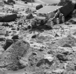 NASA's Sojourner rover is seen next to the rock "Shark," in this image taken by the Imager for Mars Pathfinder (IMP) near the end of daytime operations on Sol 52. The rover's Alpha Proton X-Ray Spectrometer is deployed against the rock. The rock "Wedge" is in the foreground. The Sojourner rover is seen next to the rock "Shark," in this image taken by the Imager for Mars Pathfinder (IMP) near the end of daytime operations on Sol 52. The rover's Alpha Proton X-Ray Spectrometer is deployed against the rock. The rock "Wedge" is in the foreground.
