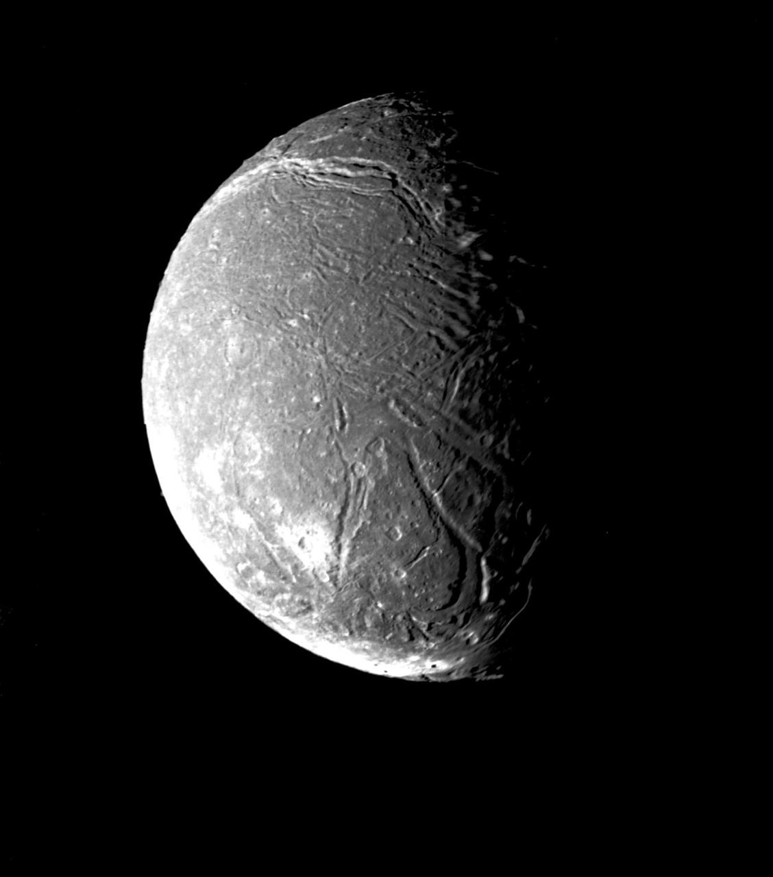 NASA Voyager 2 took this image on January 24, 1986, showing Ariel surface densely pitted with craters. Numerous valleys and fault scarps crisscross the highly pitted terrain.